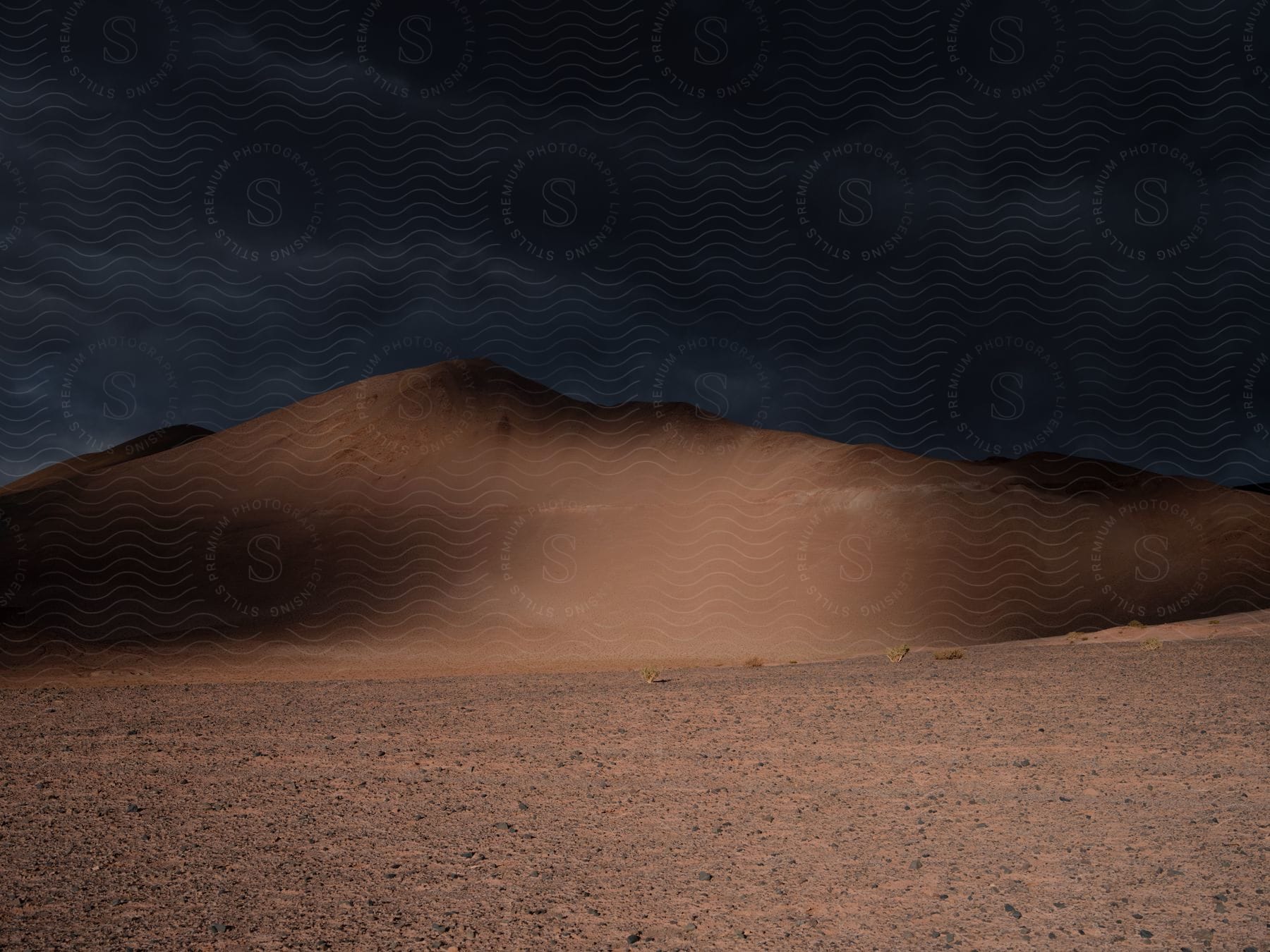Night shot of a sand bank under heavy cloudy sky in the desert
