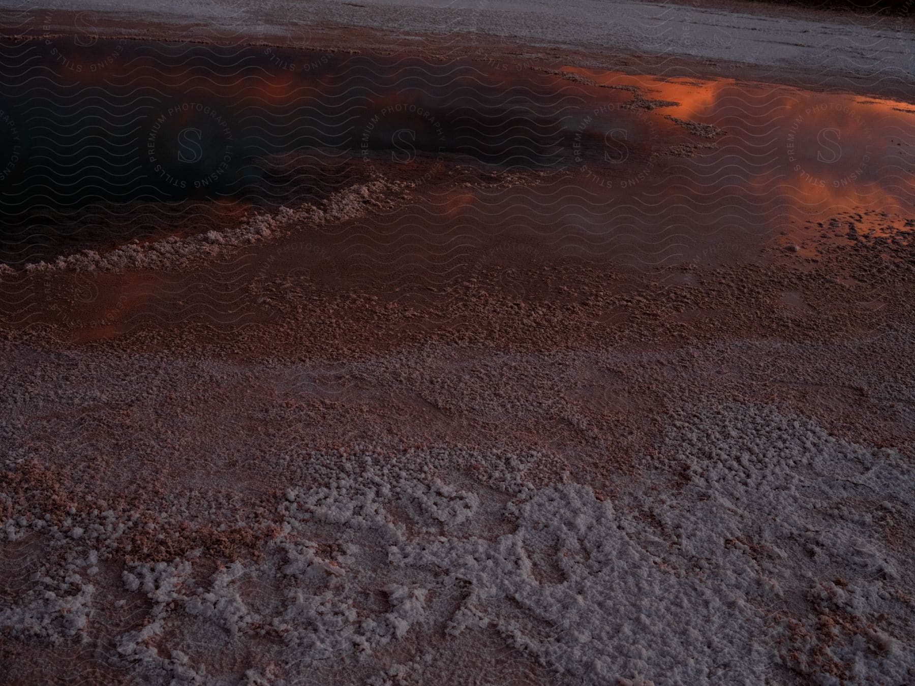 Aerial view of land with reflective water and an orange sky