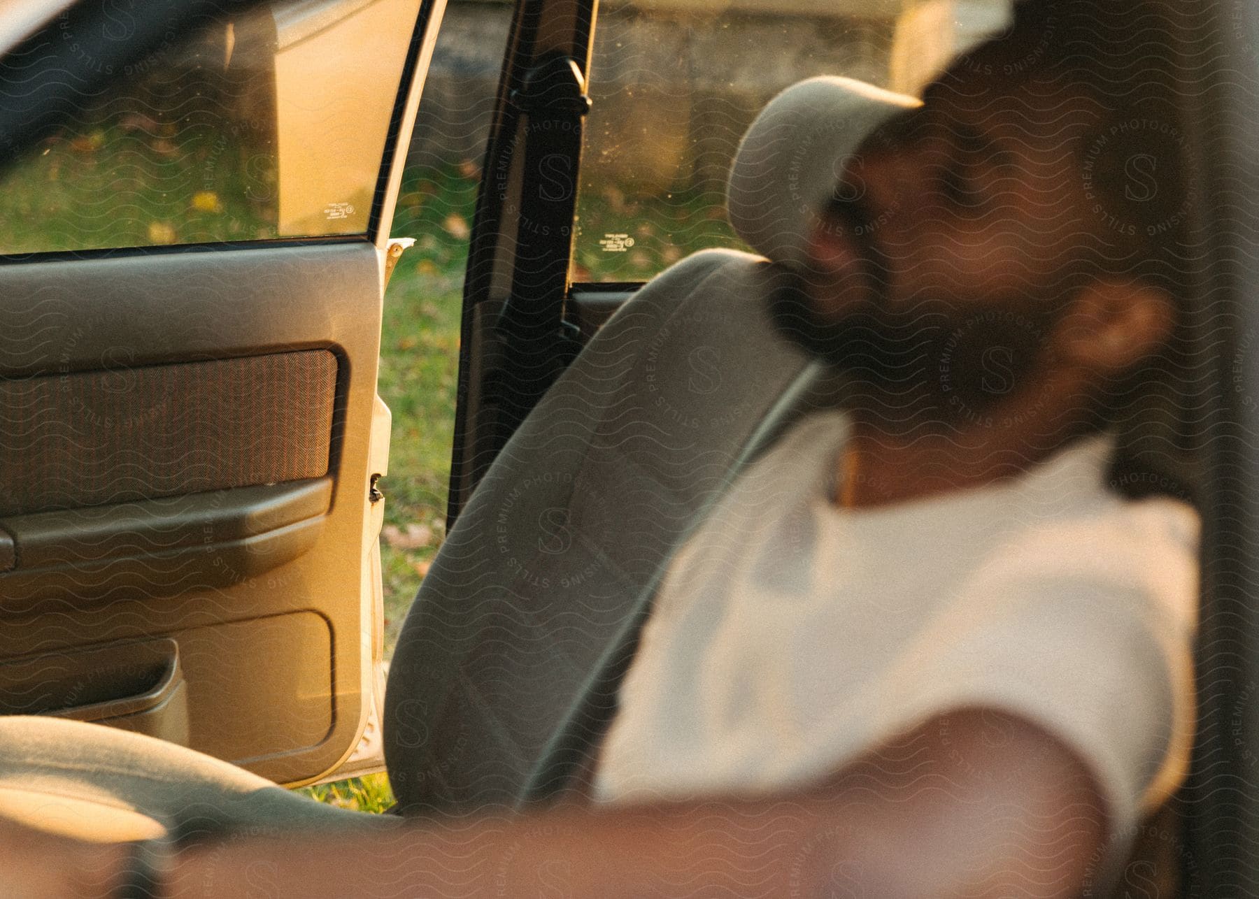 A man driving a car wearing a hat and a beard