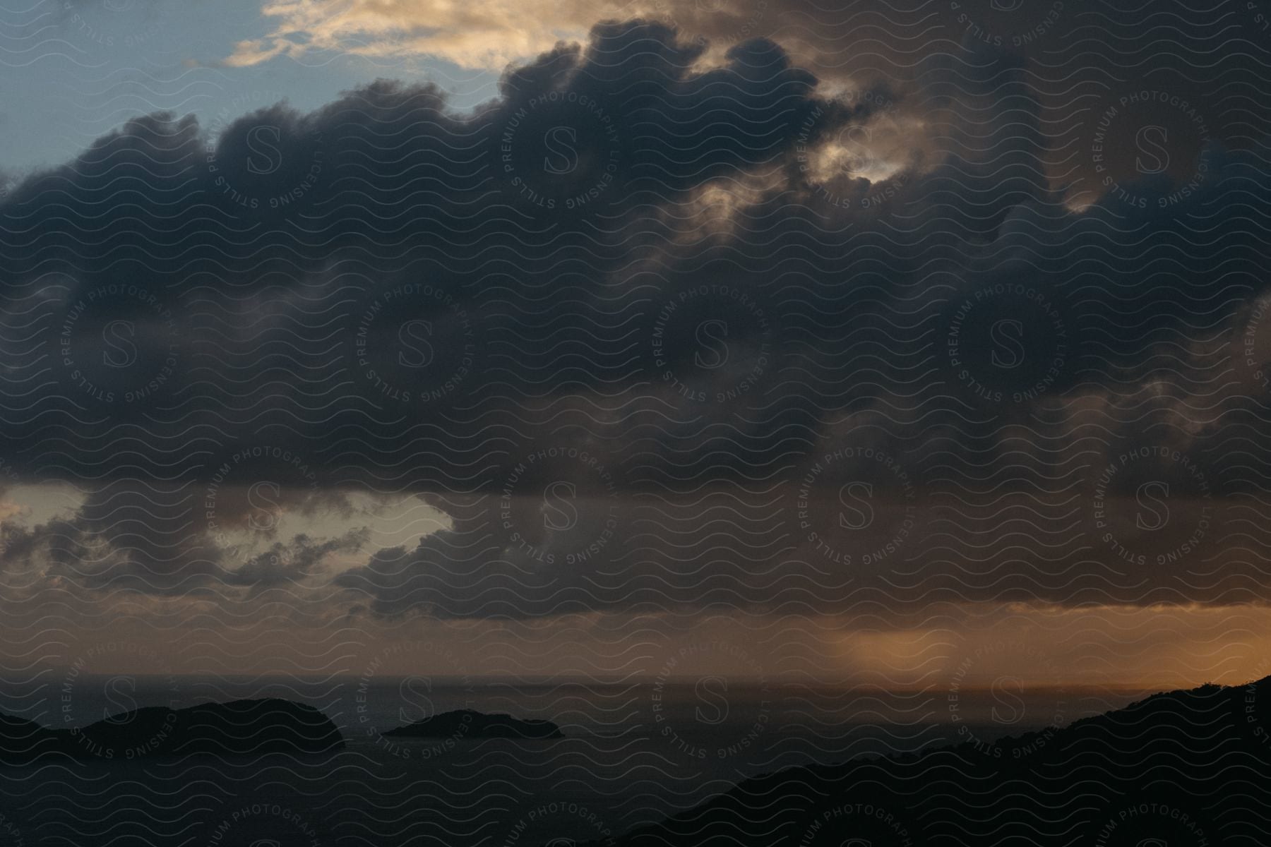 Dark storm clouds hang over the water along the coast