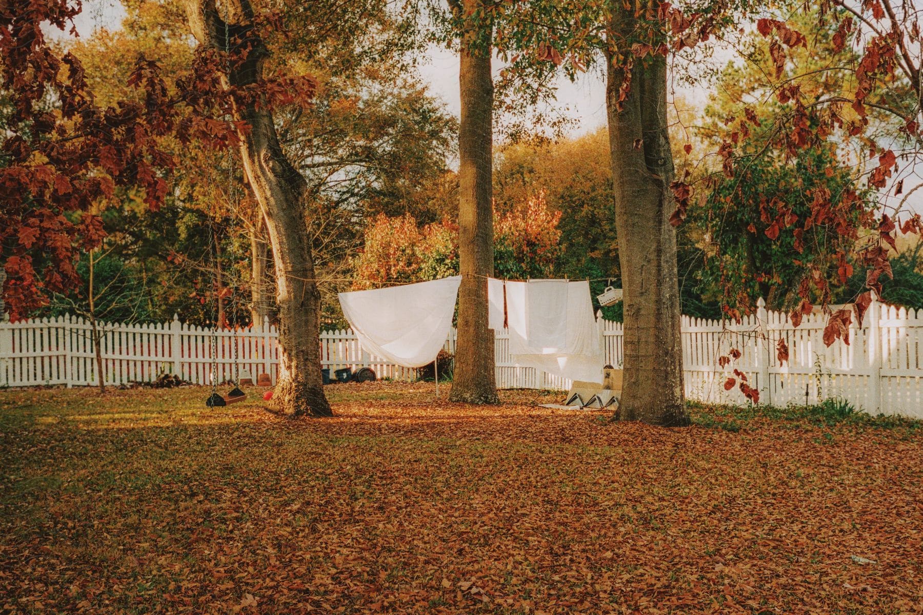 Laundry drying on a line in a backyard surrounded by a white picket fence