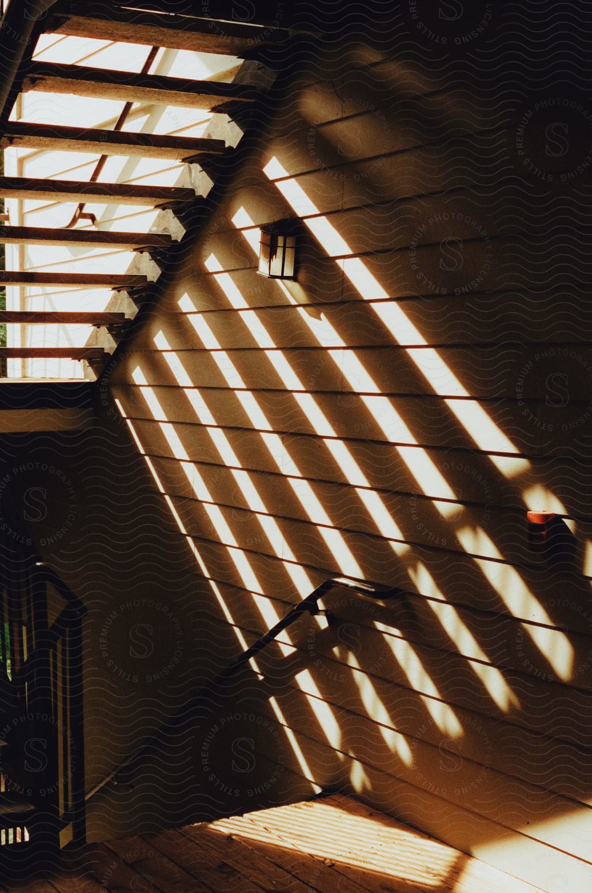 A sunlit stairway with patterned shadows on the wall and a central railing