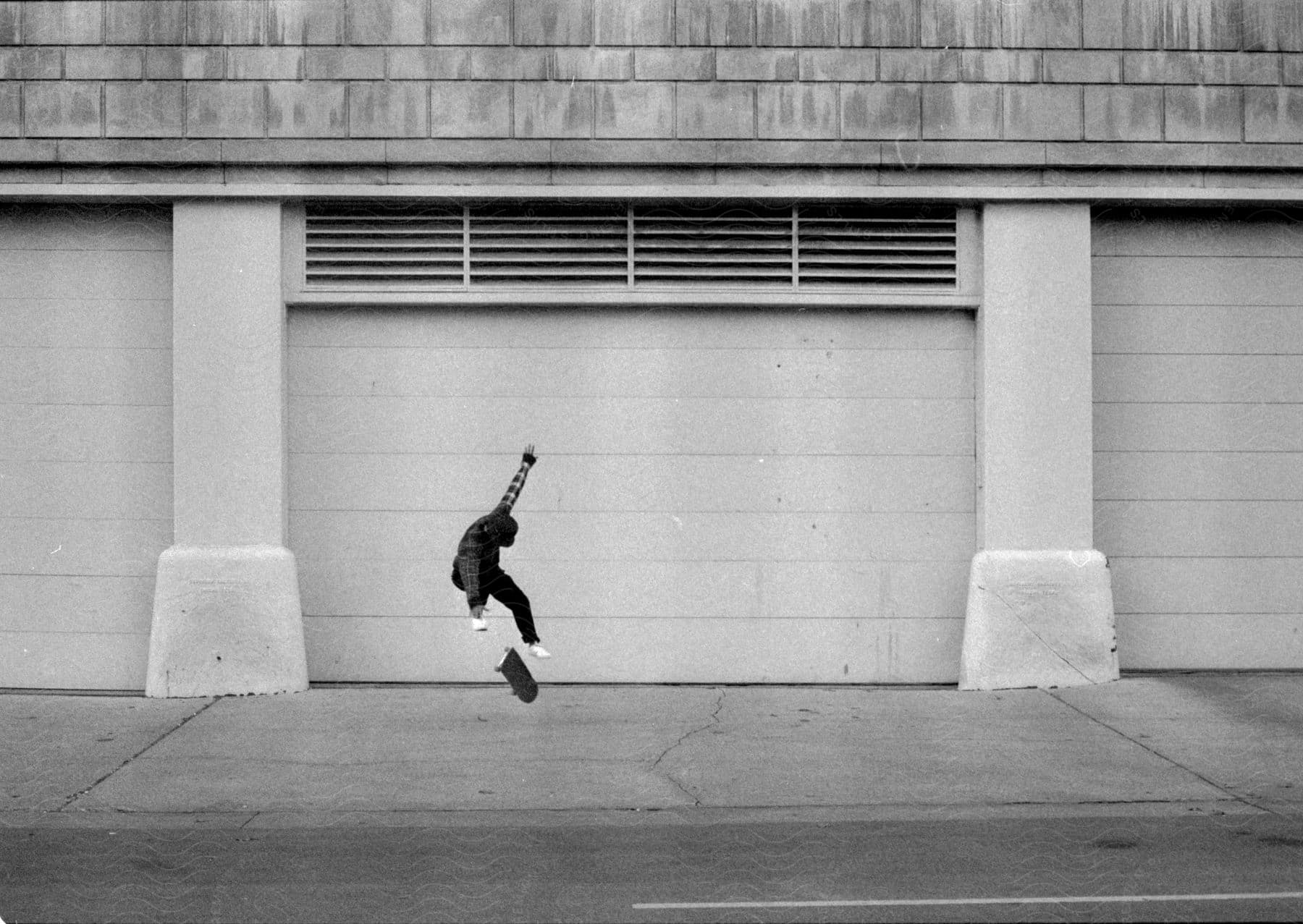 A skateboarder performs tricks while skating on a sidewalk outside a building