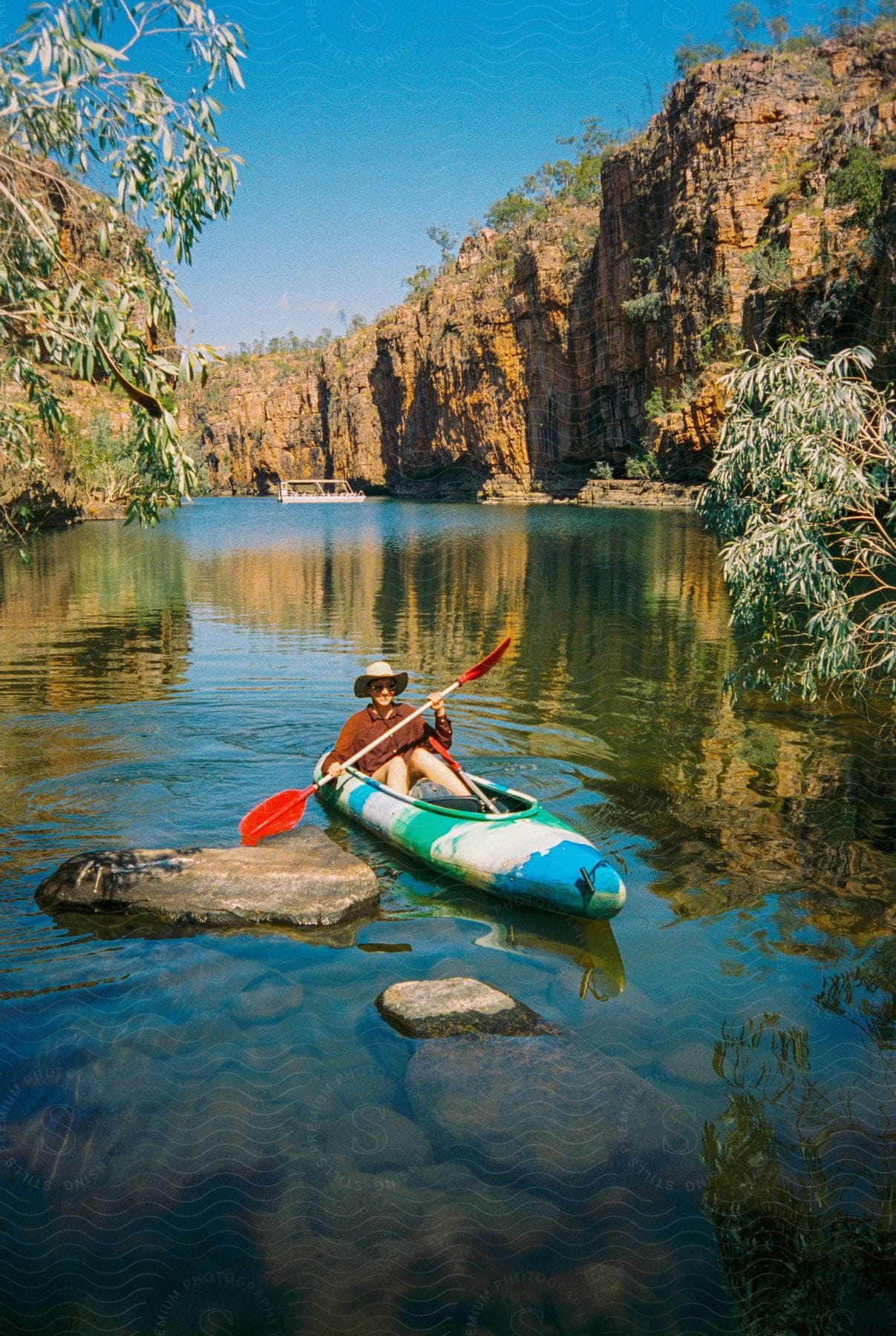 A woman kayaking in a valley surrounded by still waters