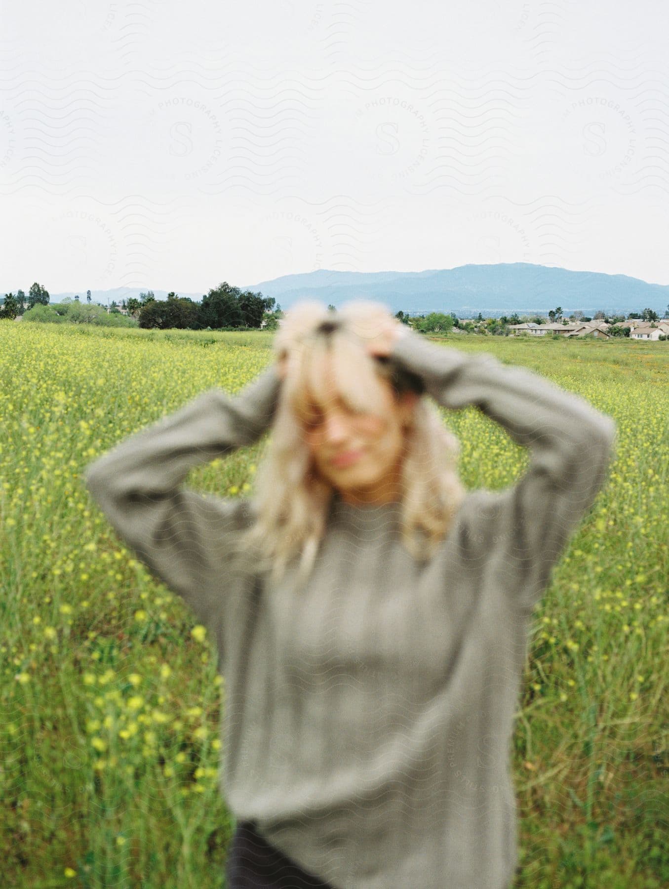 Woman with hands over her head in a blurry shot in a countryside field