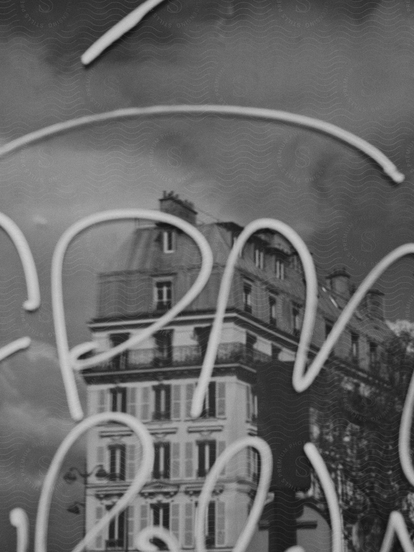 A black and white photo of a building reflected in a window with writing on it