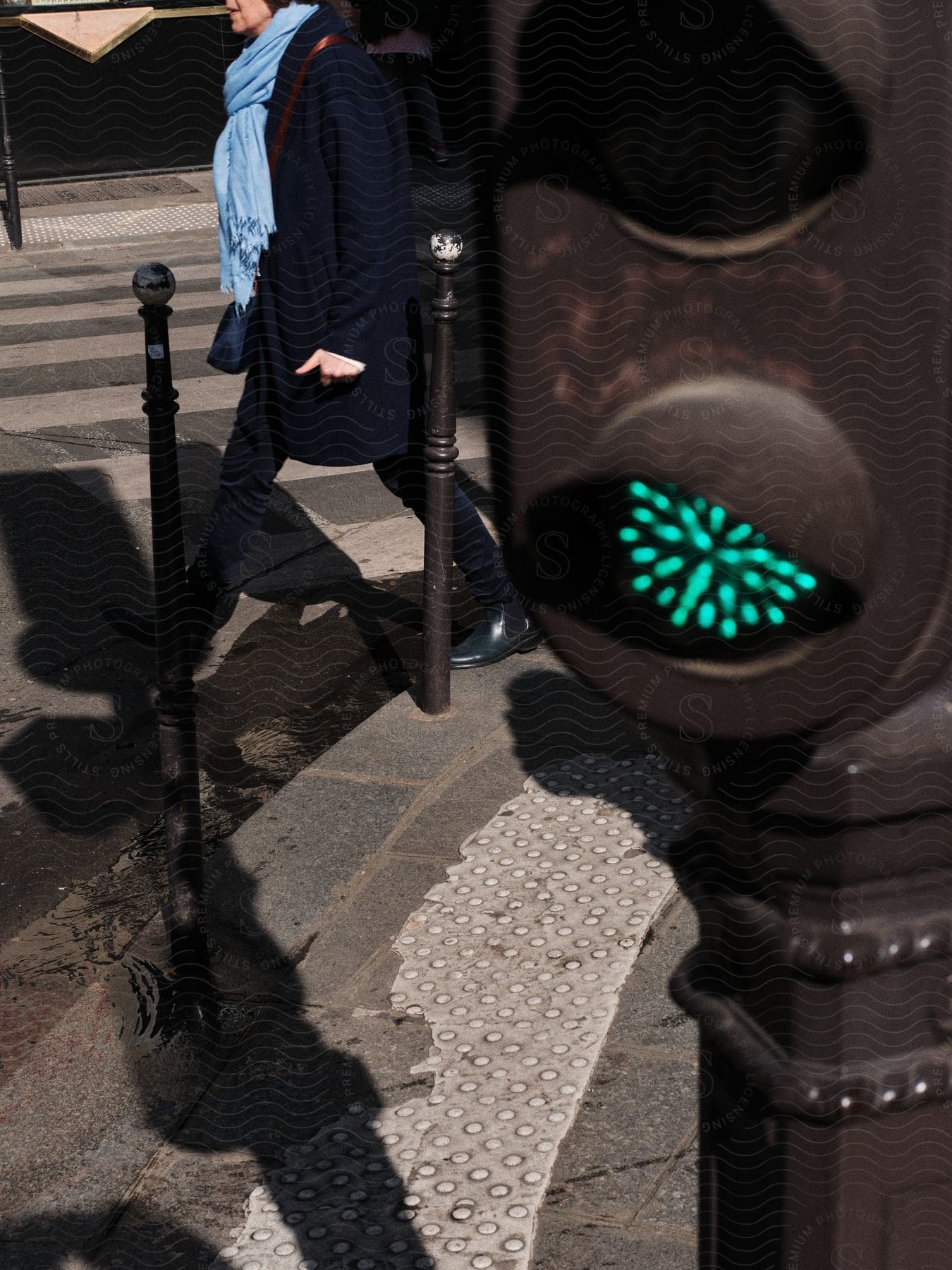 A woman walks near a crosswalk with a traffic light in the foreground