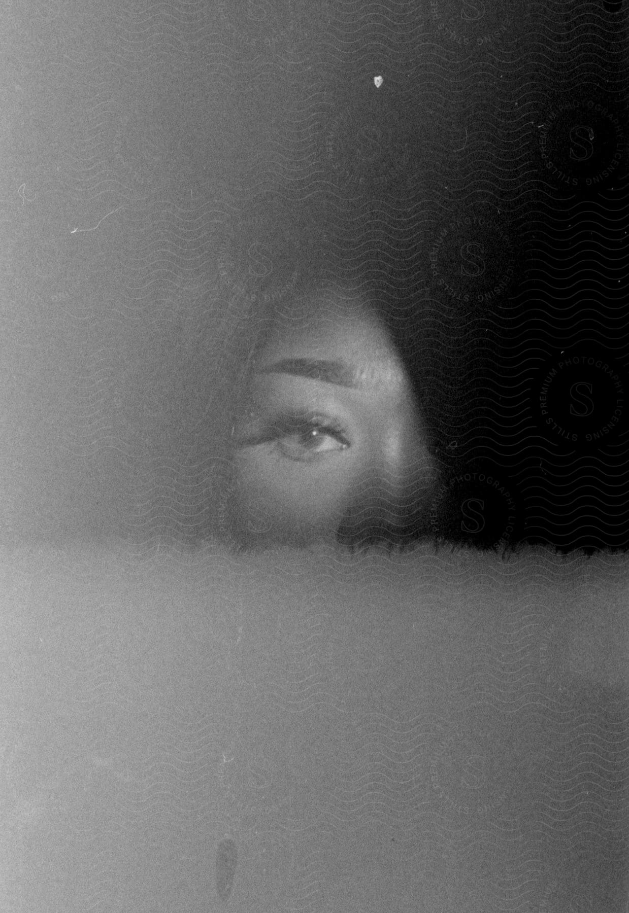 A woman with half her face covered in shadow in a black and white photograph