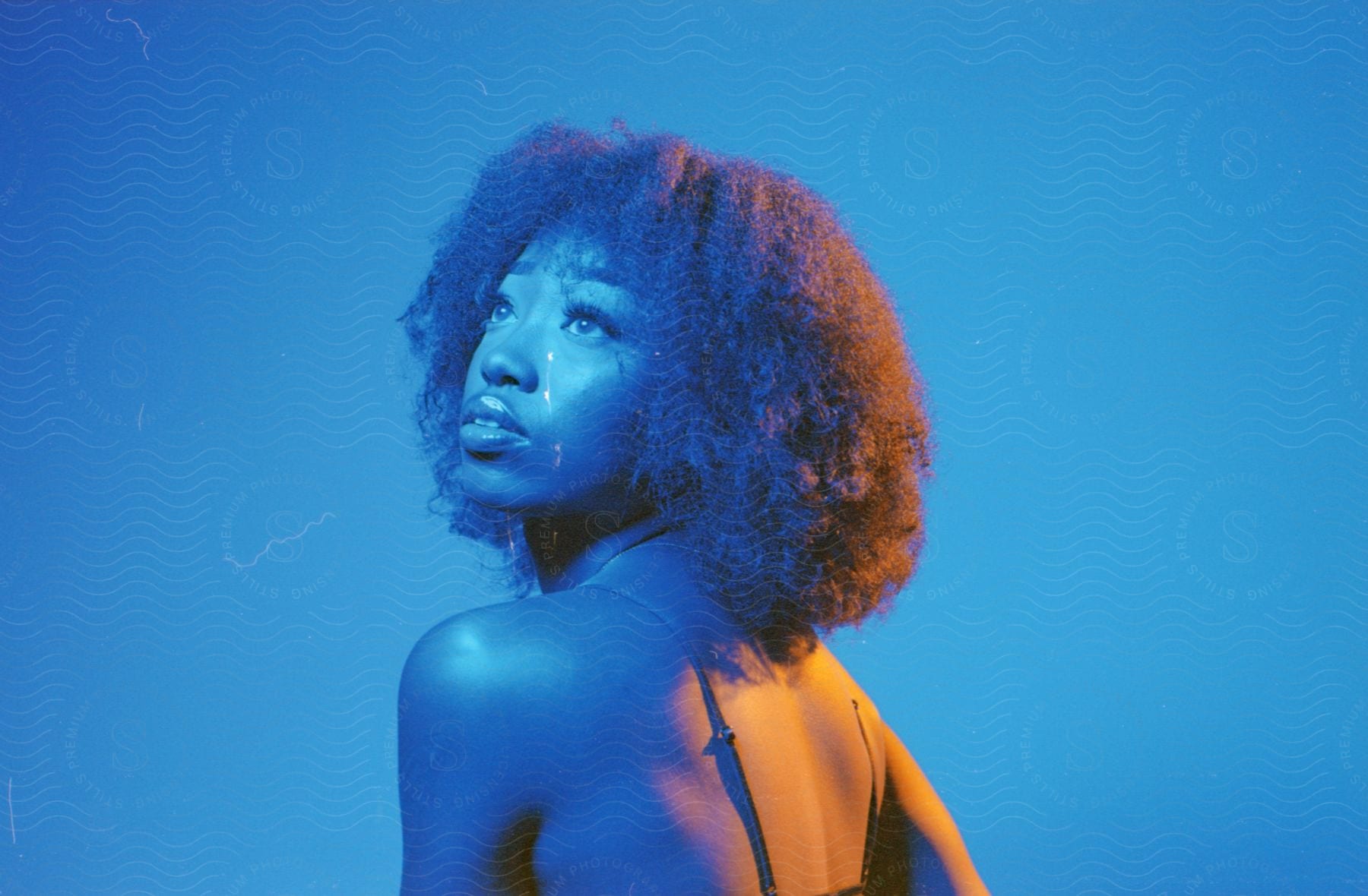 Black woman with afro hair under orange and blue contrasting lights