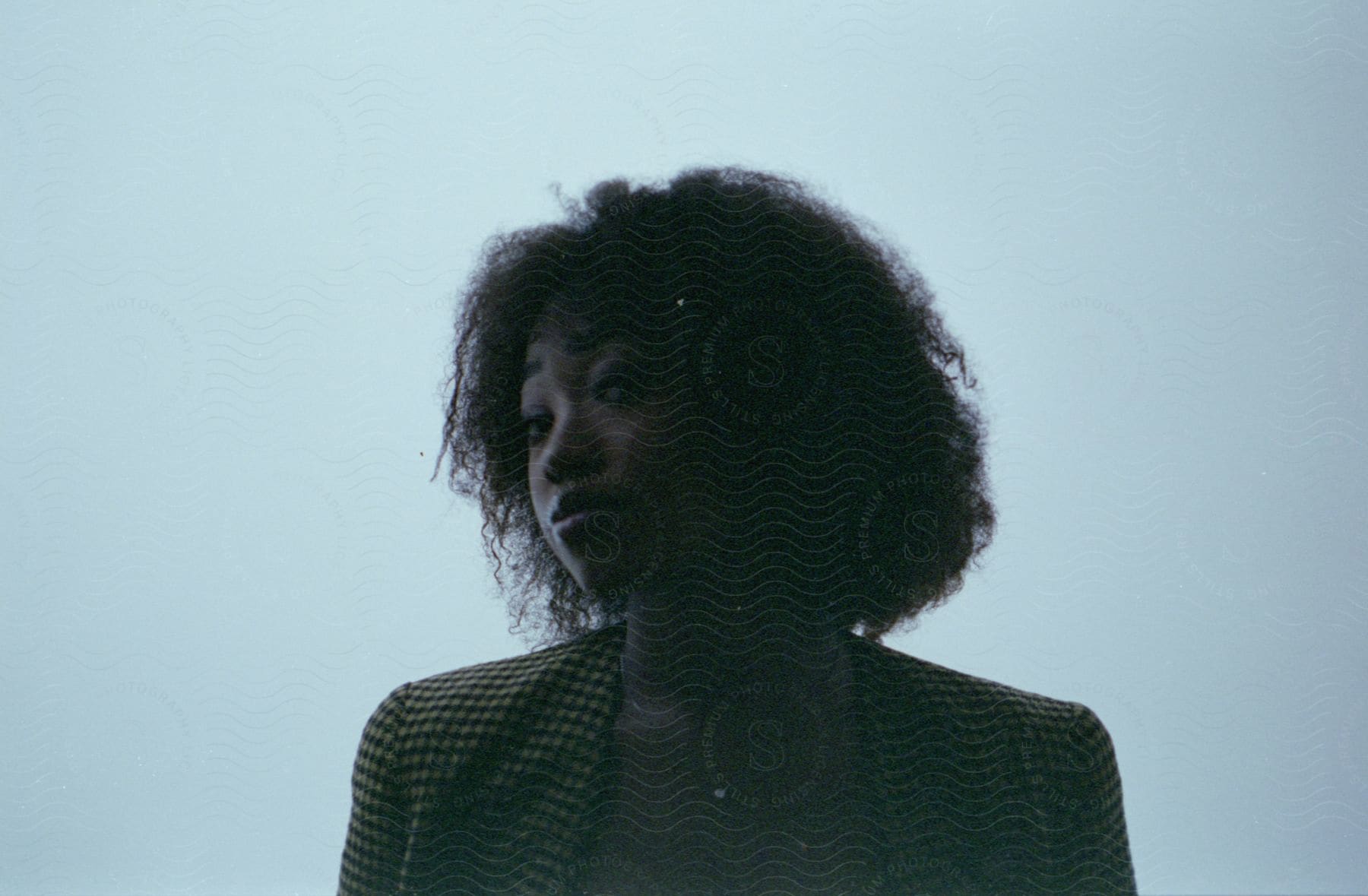 A black woman with afro hair wearing a suit posing in a studio setting