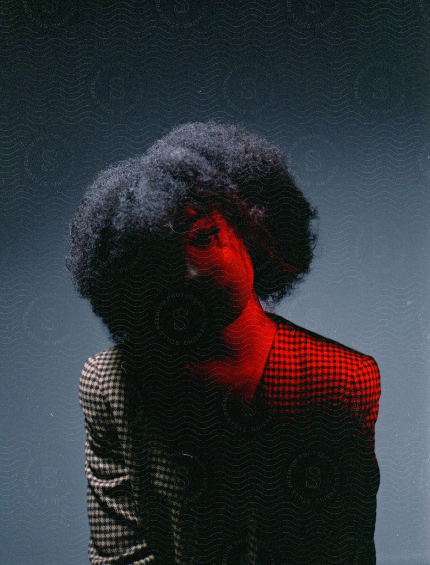 Young attractive woman with an afro sitting in the shadows looking at the camera