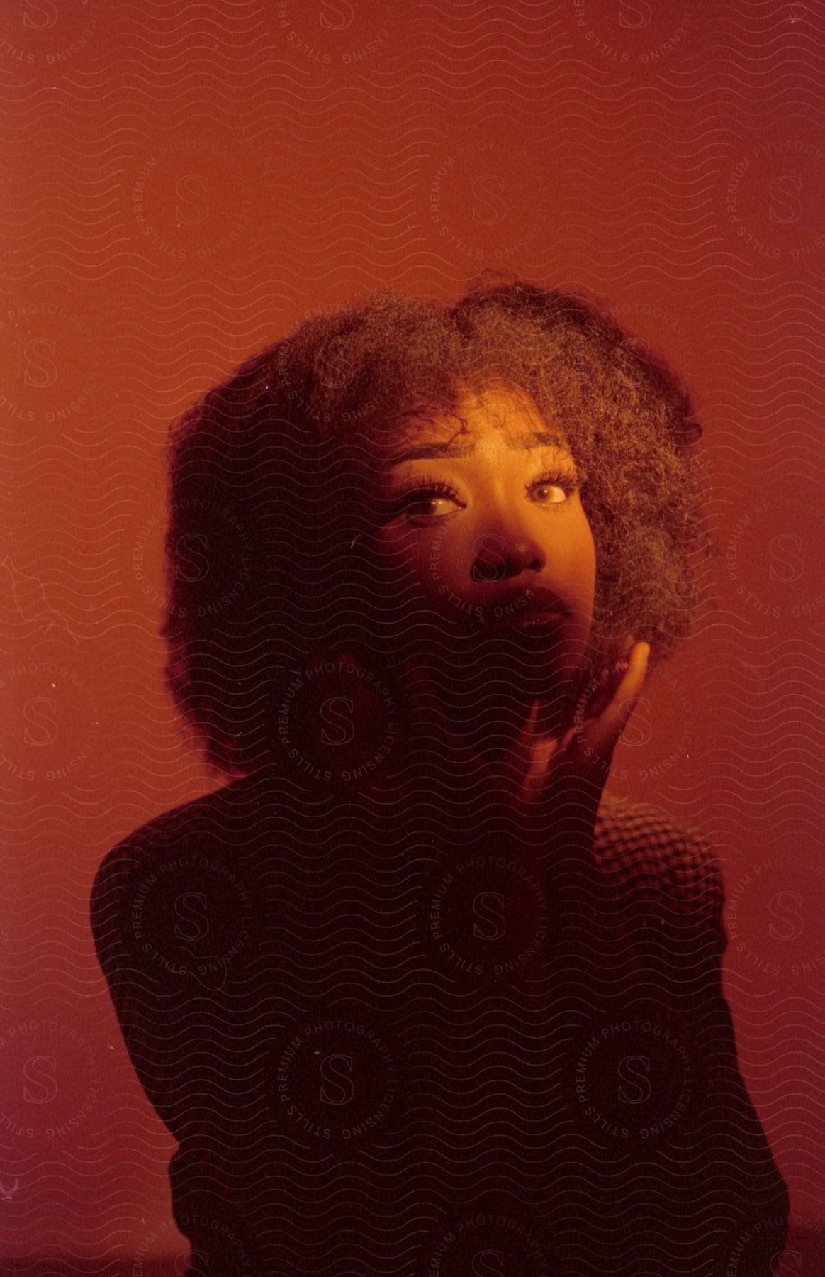 Black woman with afro hair and hands around neck on intense red background