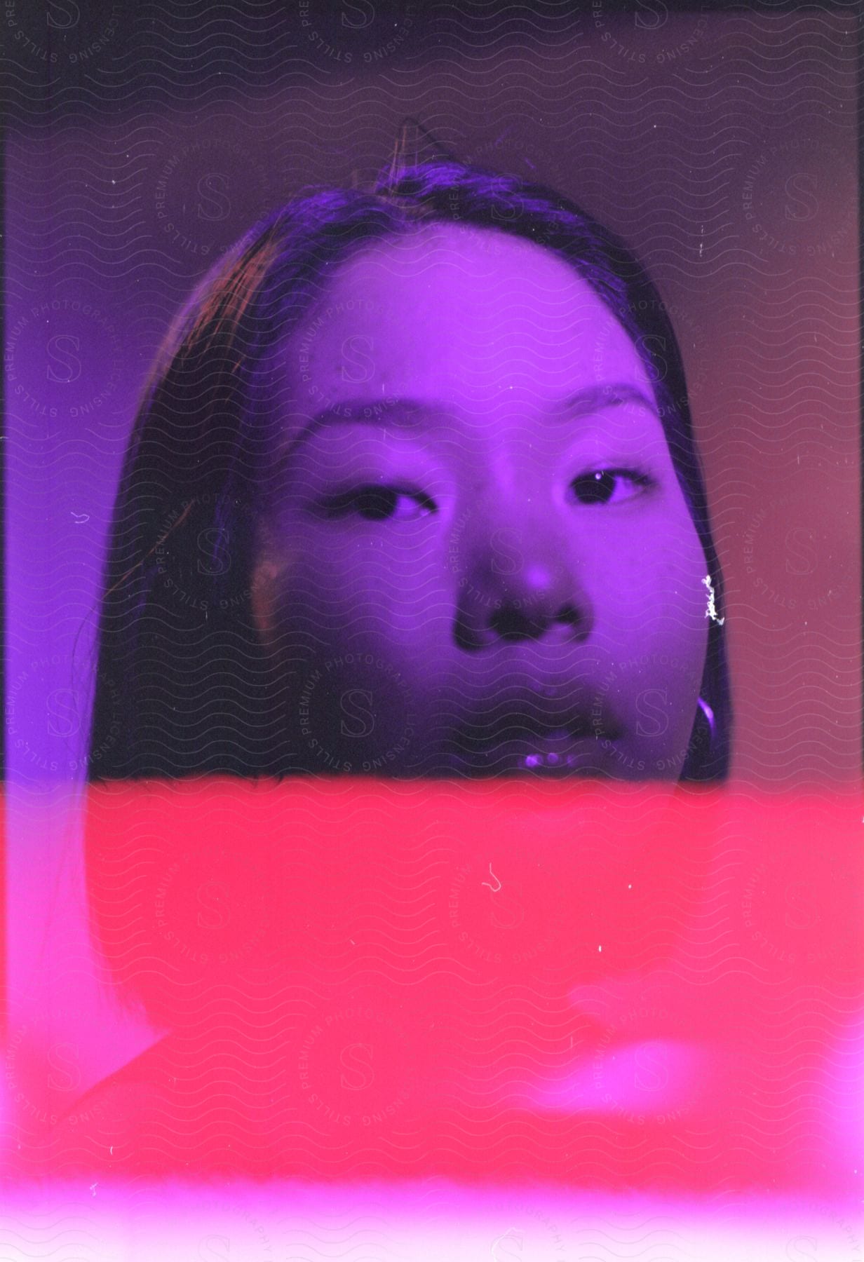 A young woman in purple lighting with pink overlap from the chin down.