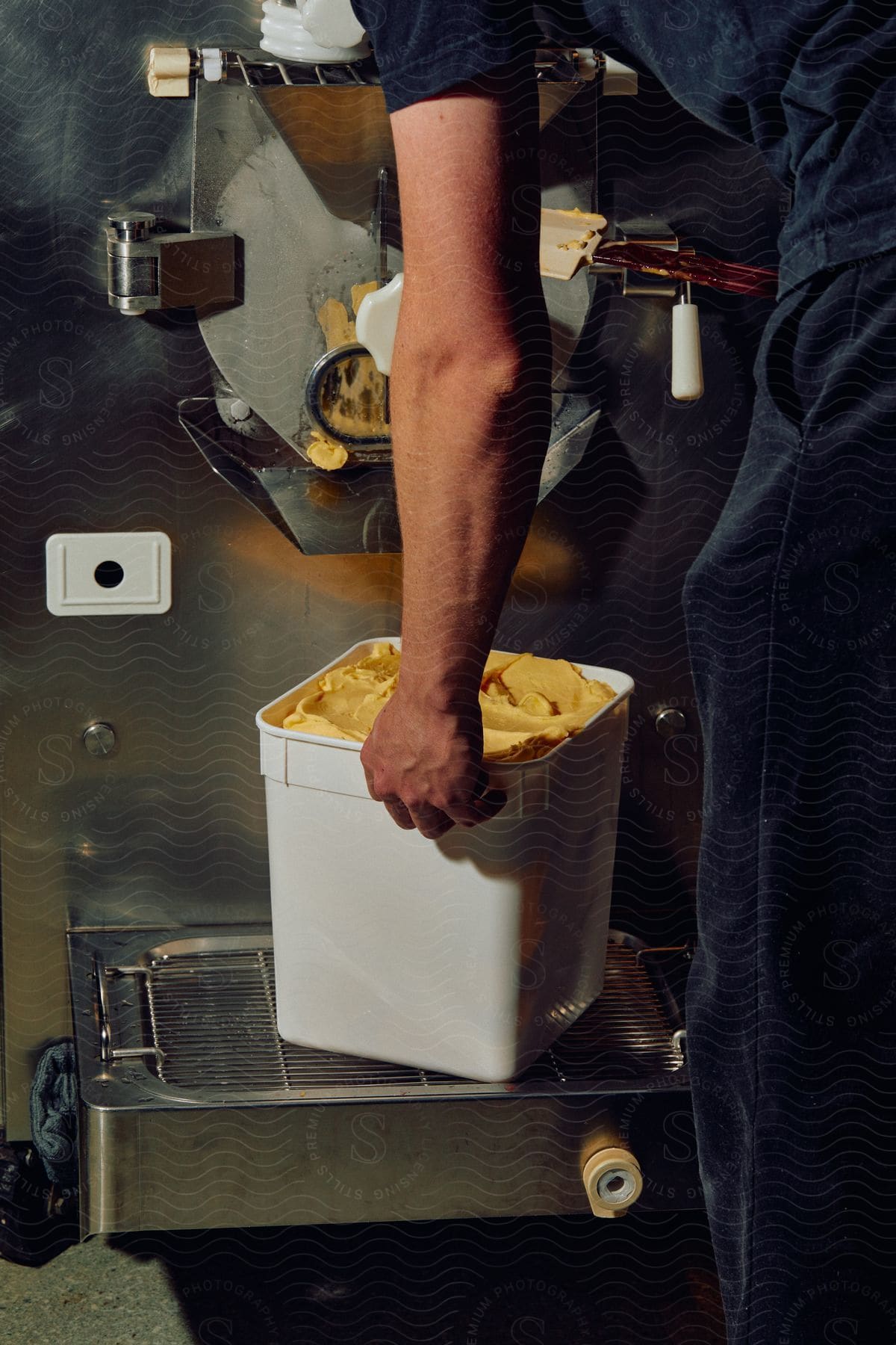 Stock photo of working man picking up a bucket of pasta in an industrial setting
