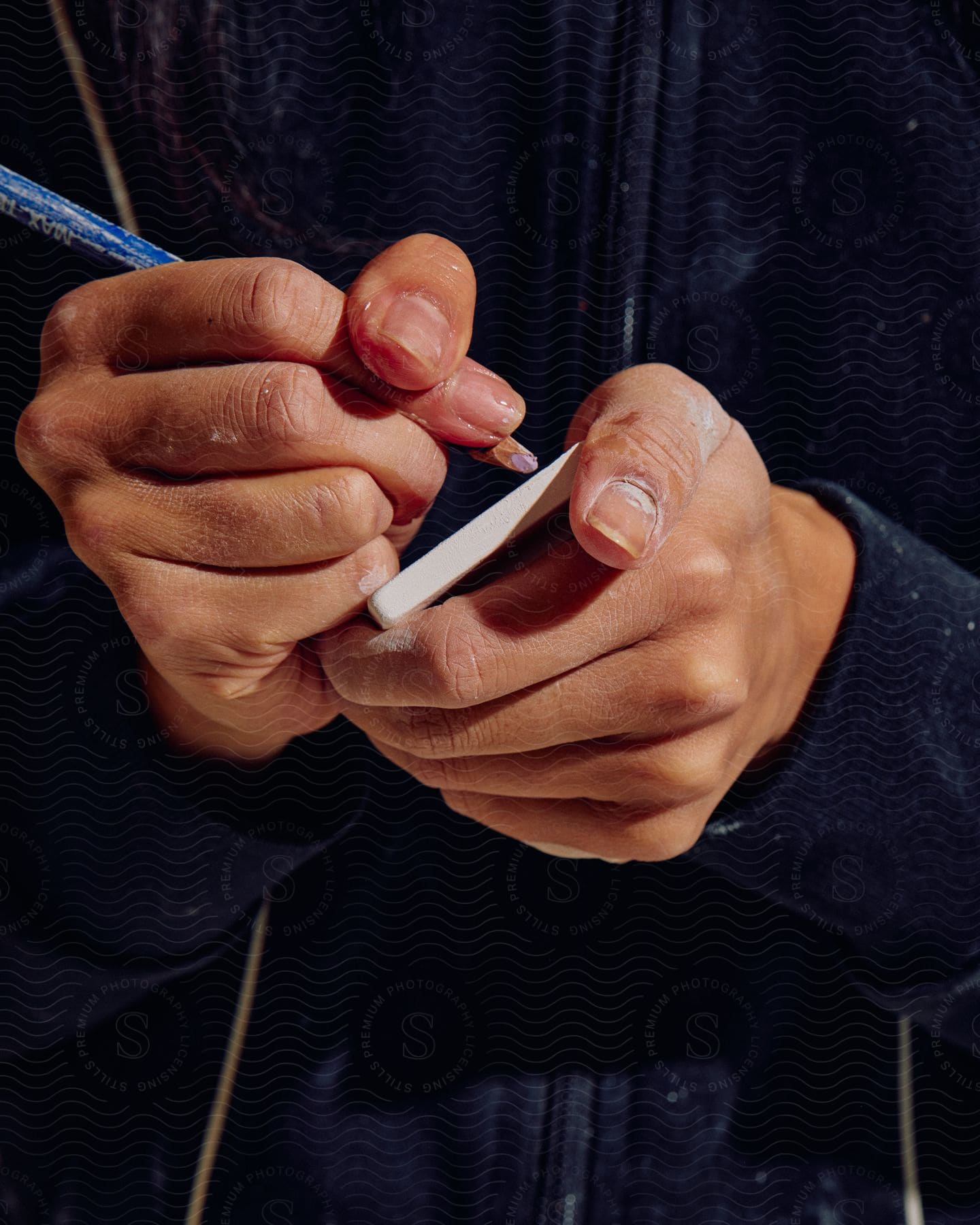 A person holding a colored pencil up close