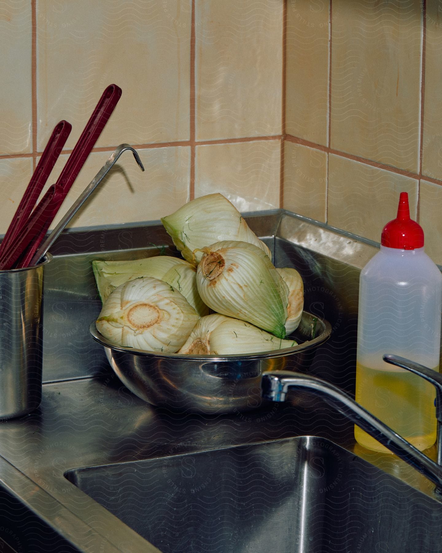 A bowl of cooked cabbage sits next to a metal sink in a kitchen