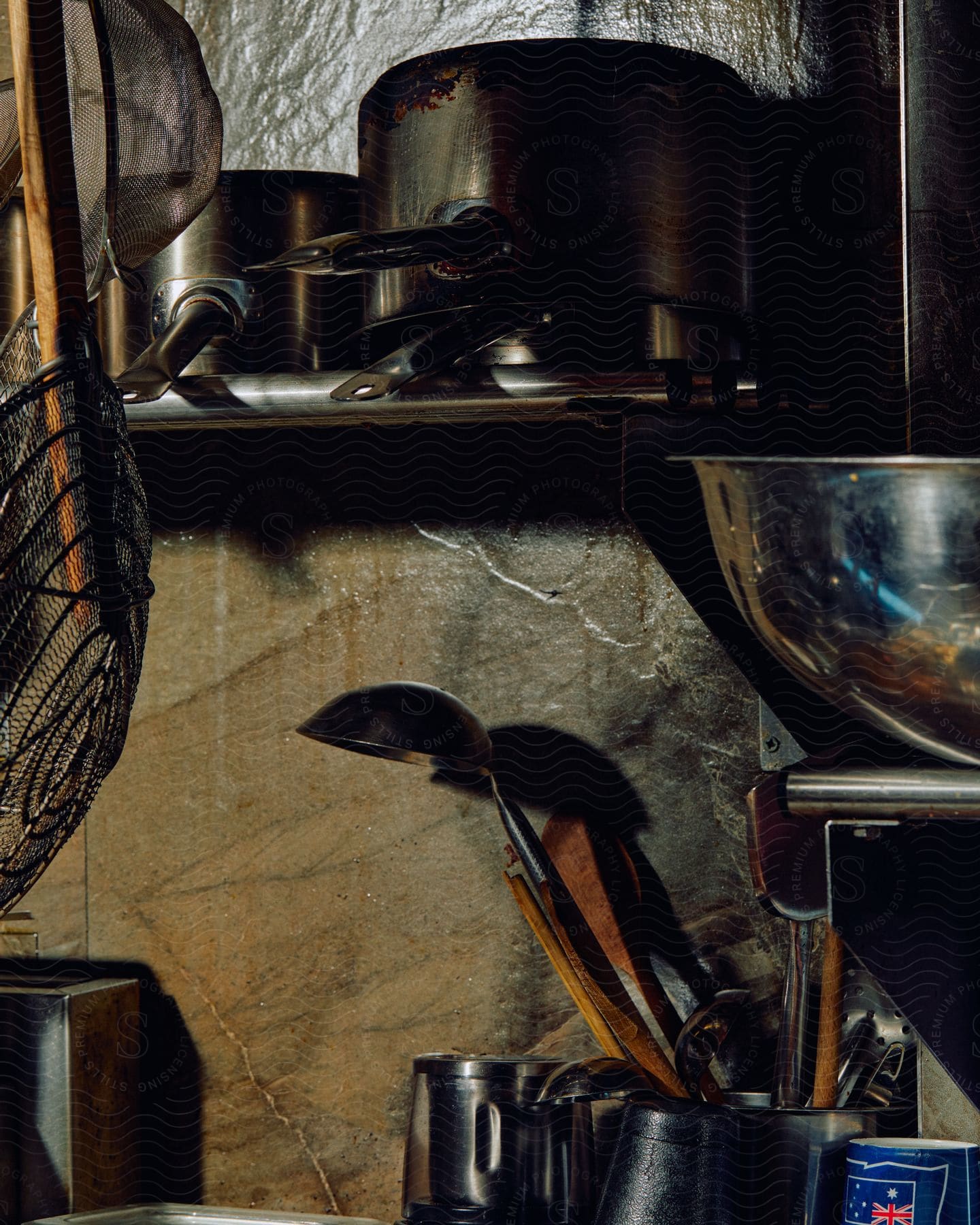 Kitchen utensils stored against a concrete wall in a kitchen