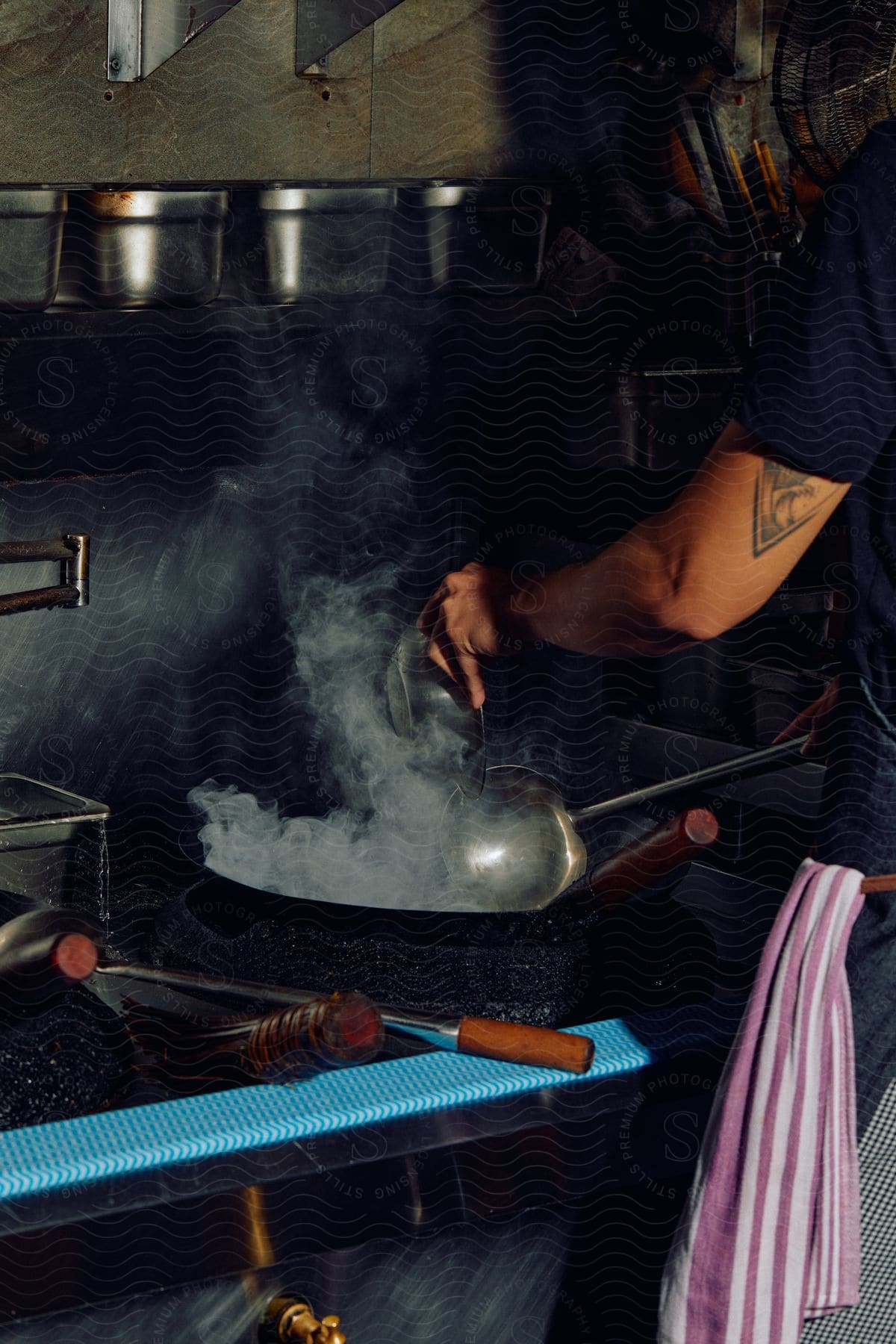 Young chef stirring food on a wok in the restaurant kitchen