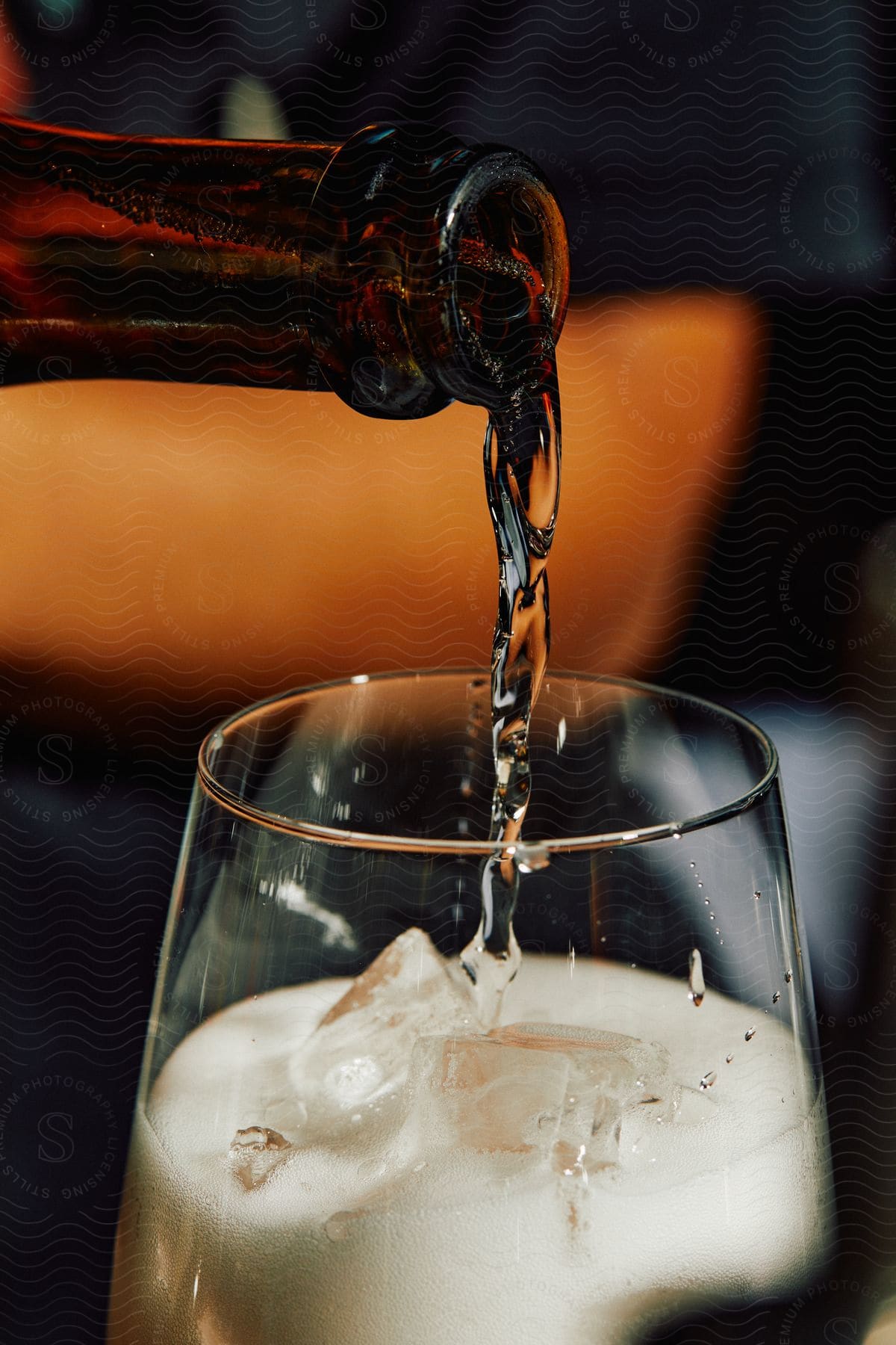 Close up of champagne pouring from a bottle into a glass filled with ice