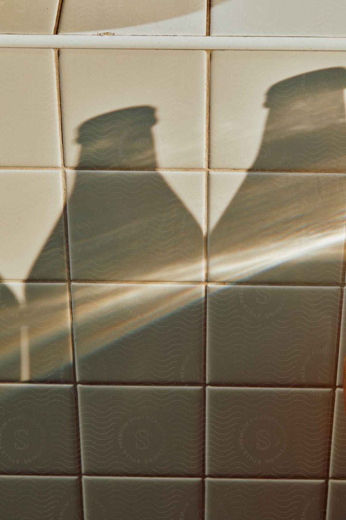 Bottles cast shadows on tile wall