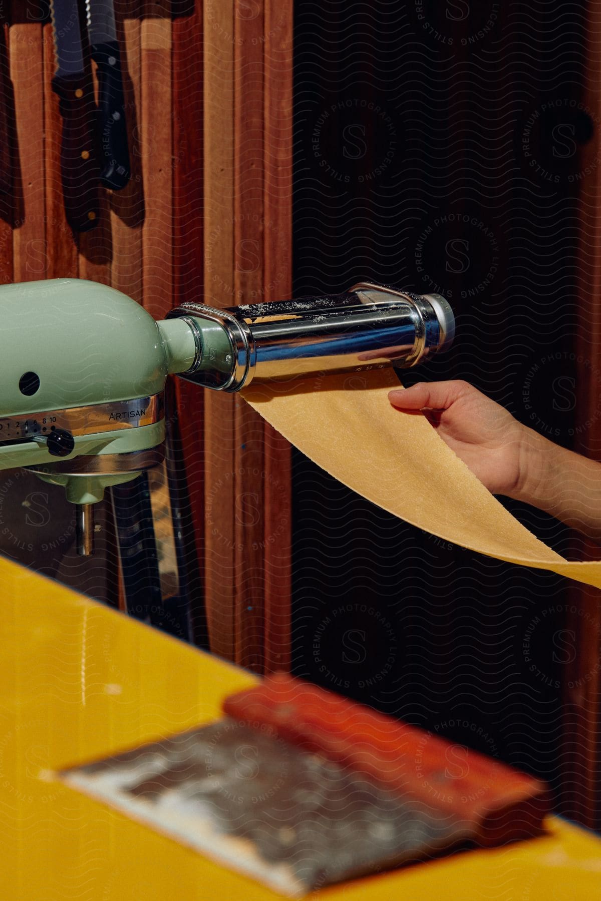 Person operating an industrial food machine in a kitchen preparing a pasta sheet