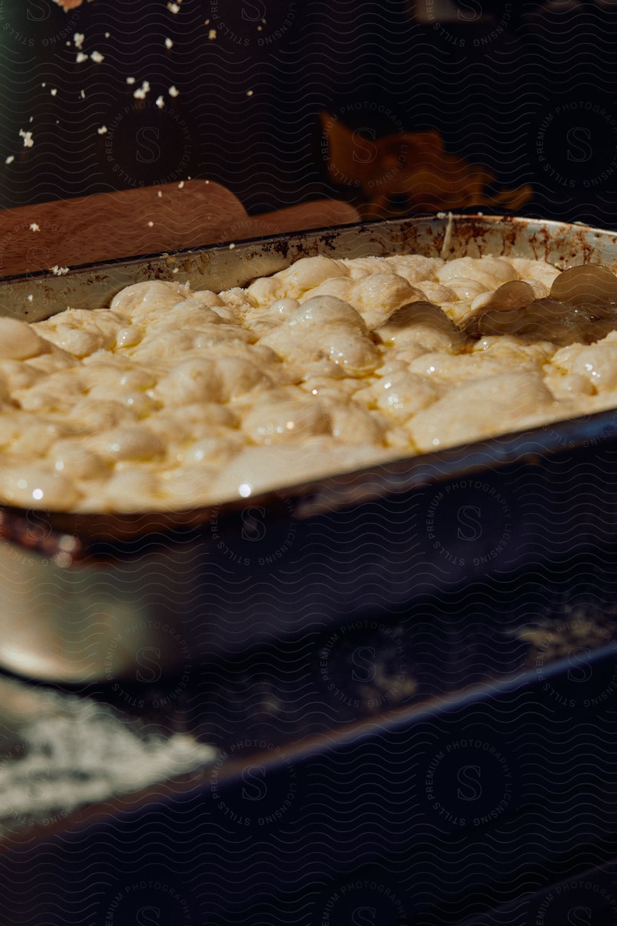 Close up of seasoning being sprinkled over a dish being cooked inside a metal tray