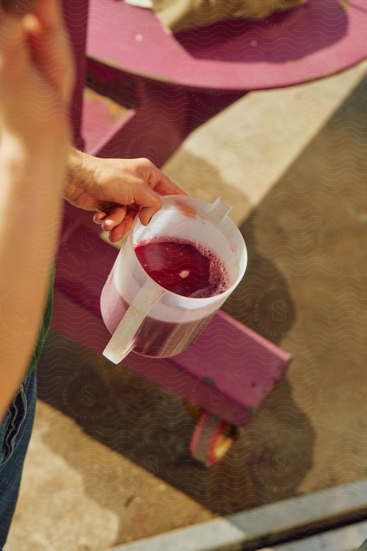 A man holding a plastic jar filled with a thick magenta liquid