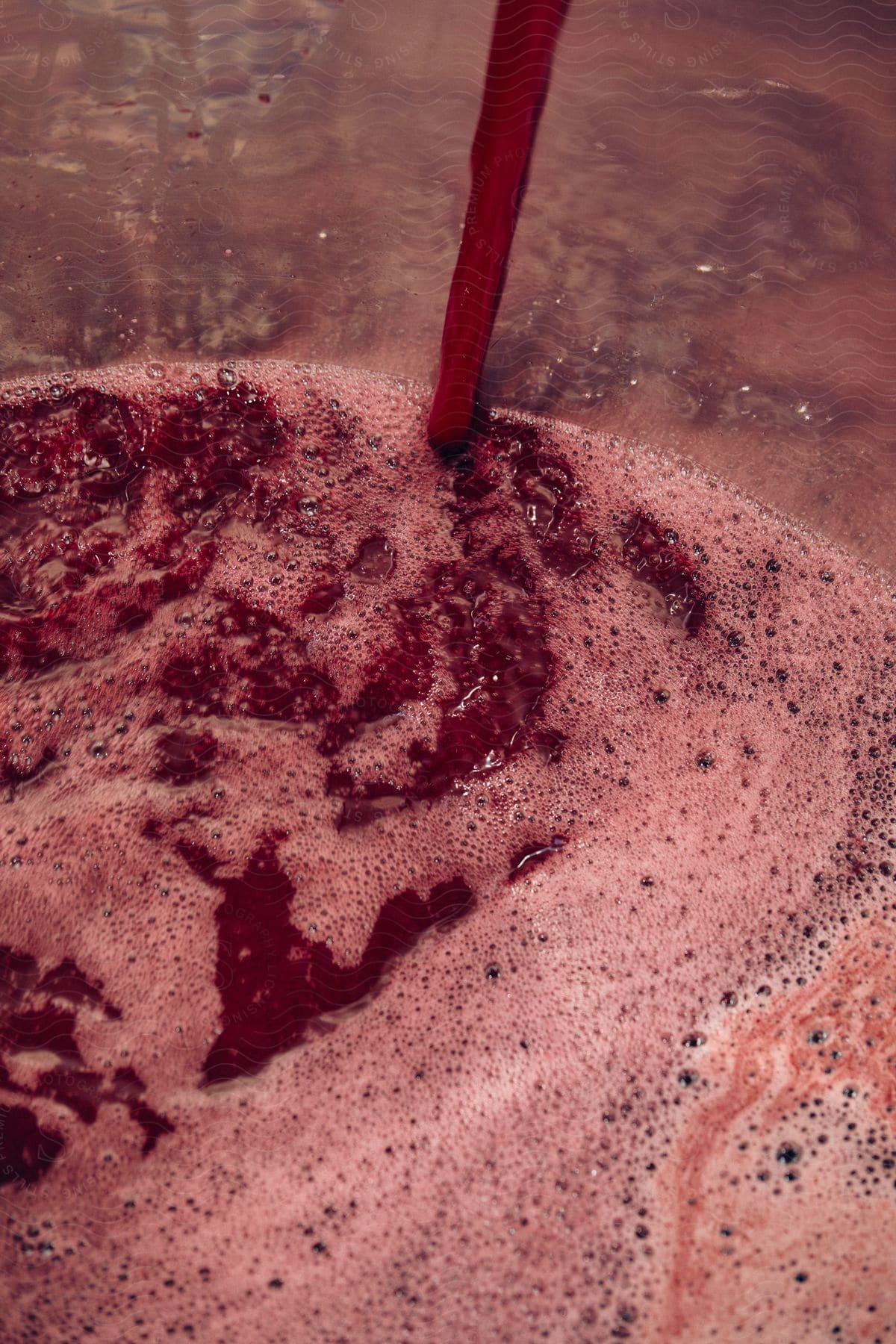 Pouring red wine mash on a metal tub in a wine country setting