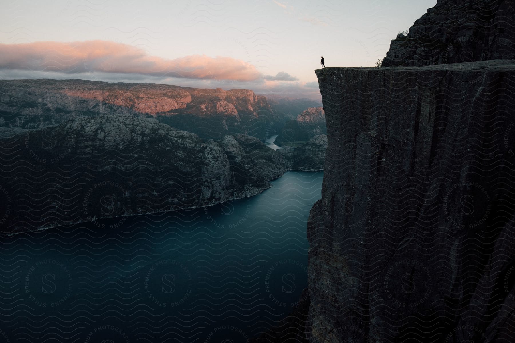 A person standing on a cliff overlooking the water