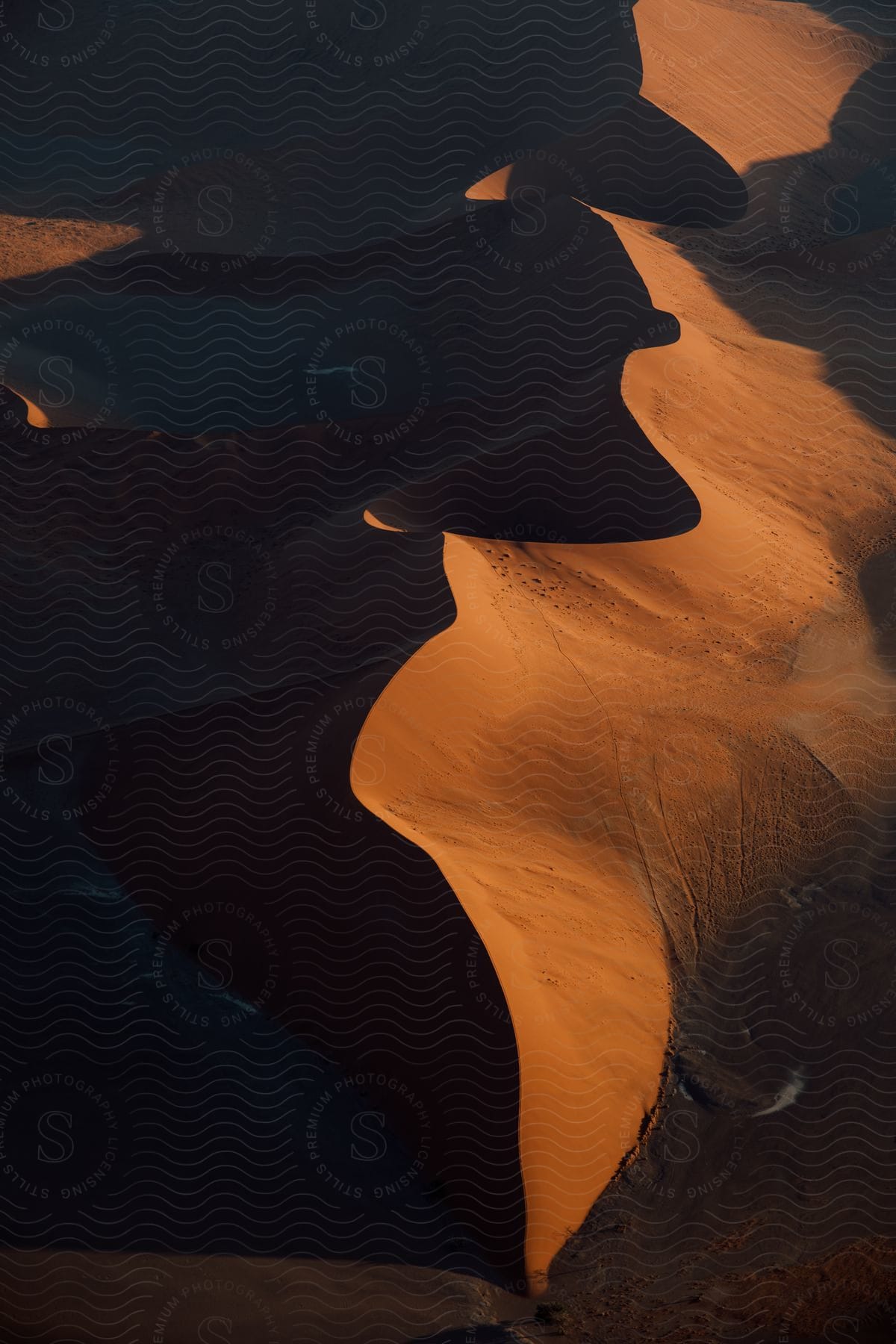 A desert dune landscape with water and a clear sky