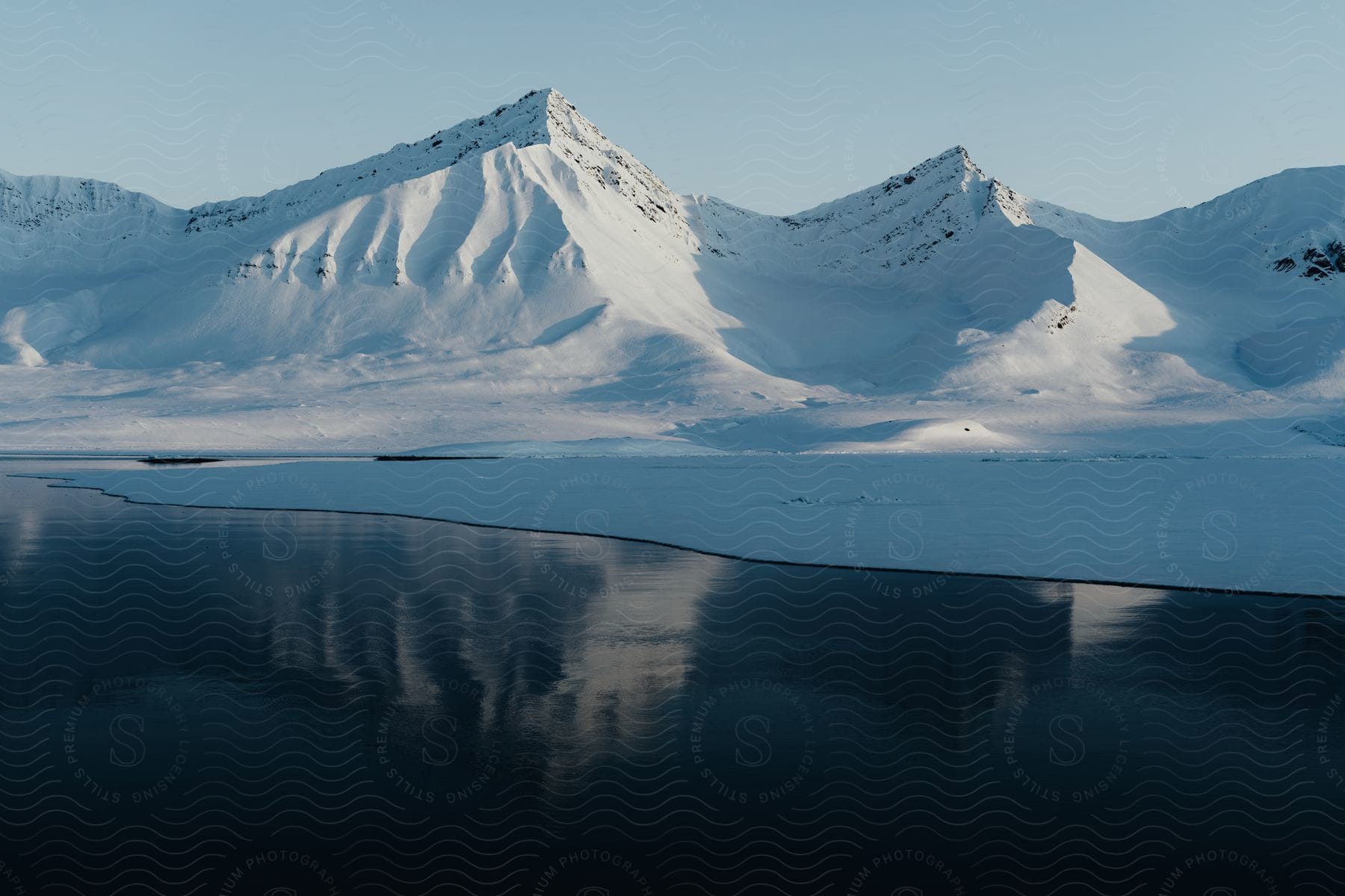 A lake with icy waters and snowcovered hills in the background