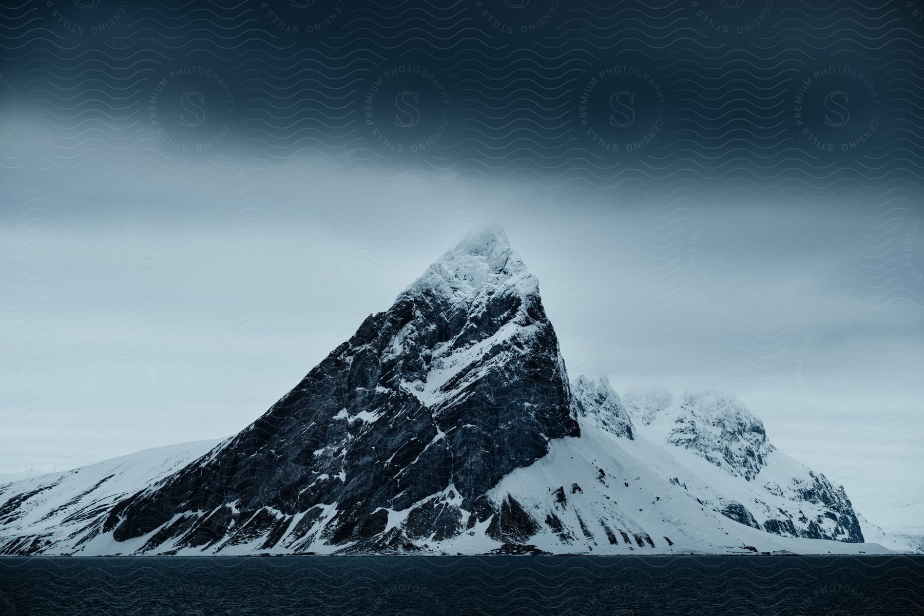 A winter scene of mountains in svalbard showcasing the icy landscape under a cloudy sky