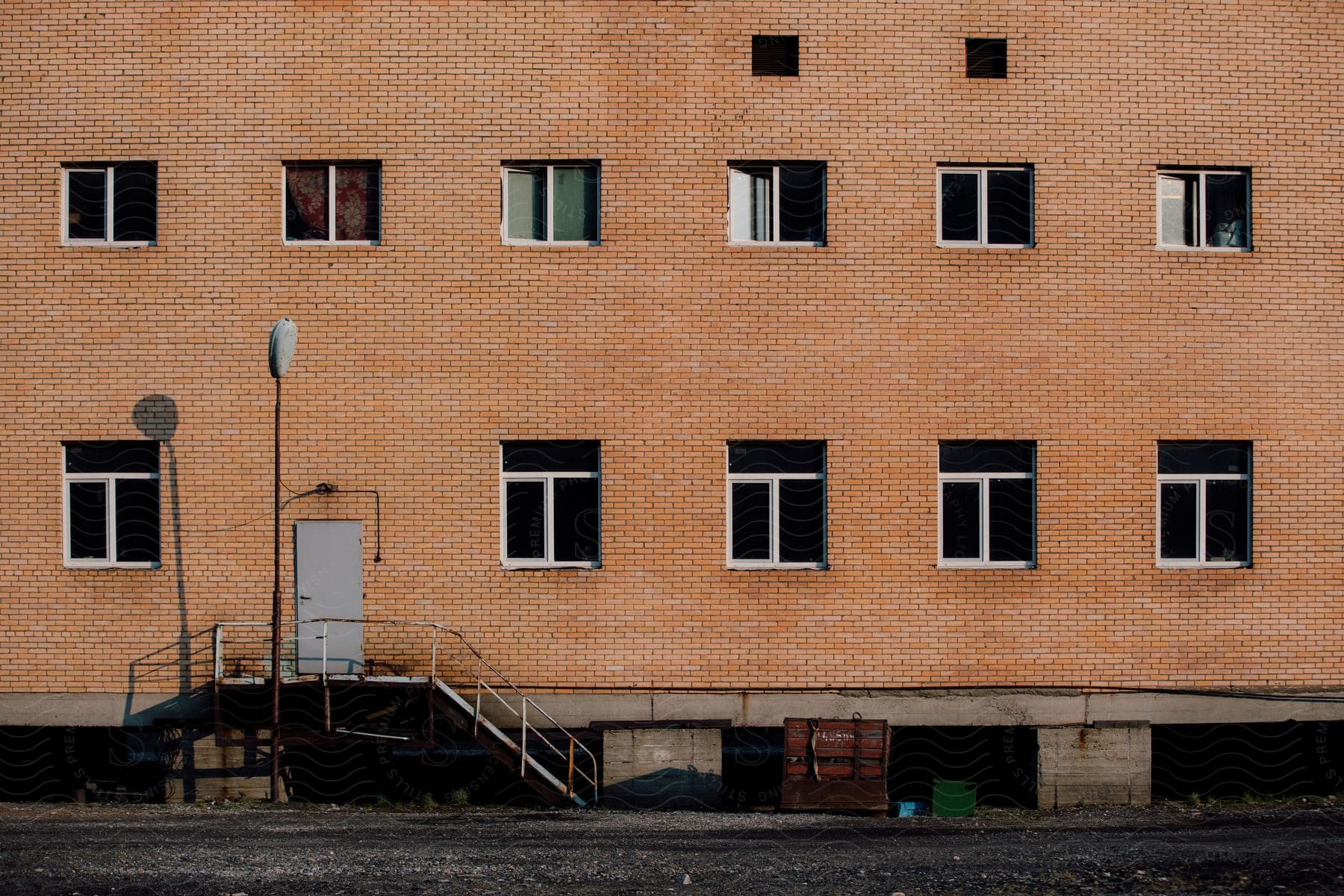 An abandoned office building with blown out windows in a residential area during the summer