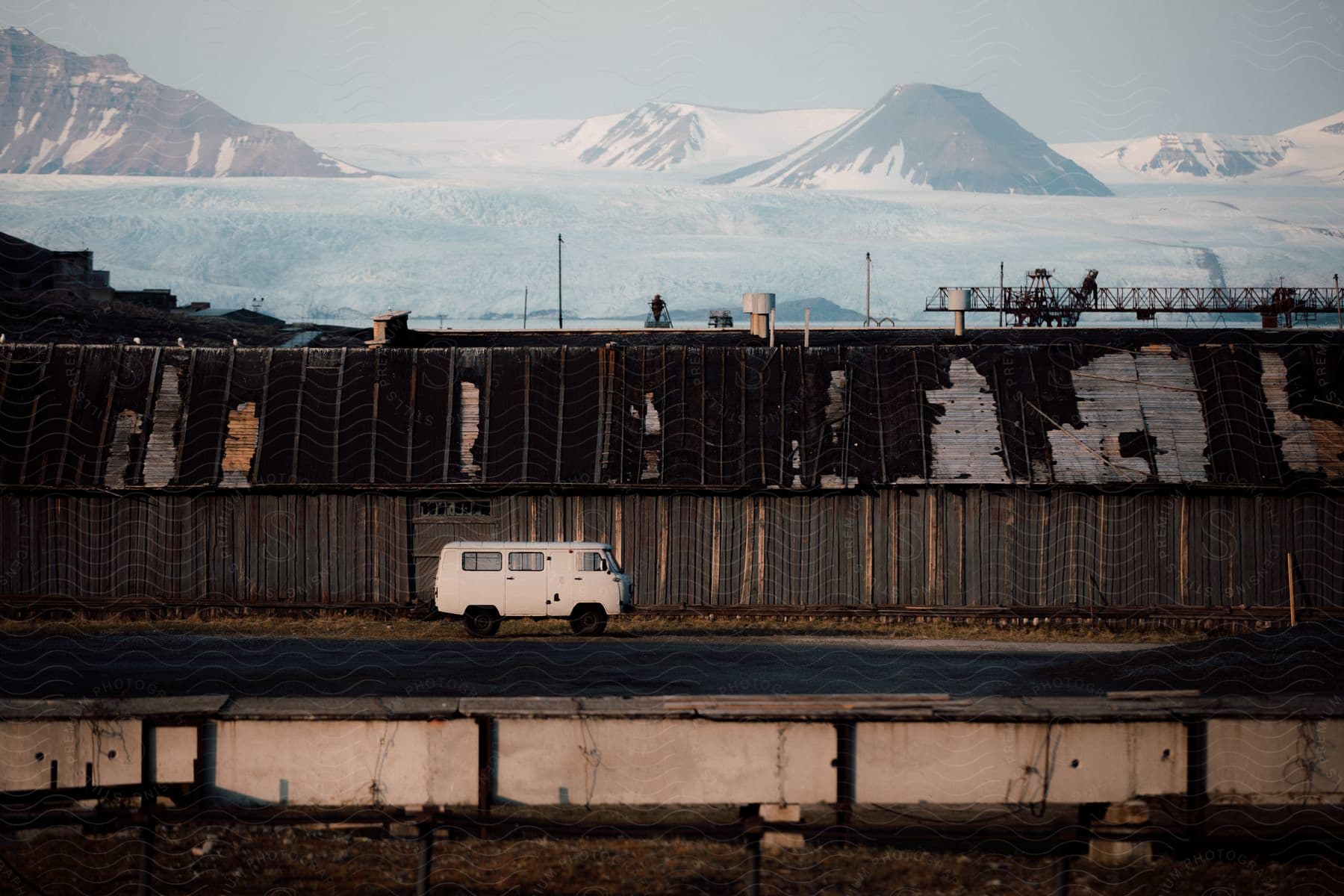 White volkswagen van parked outside a warehouse next to a glacier in the mountains