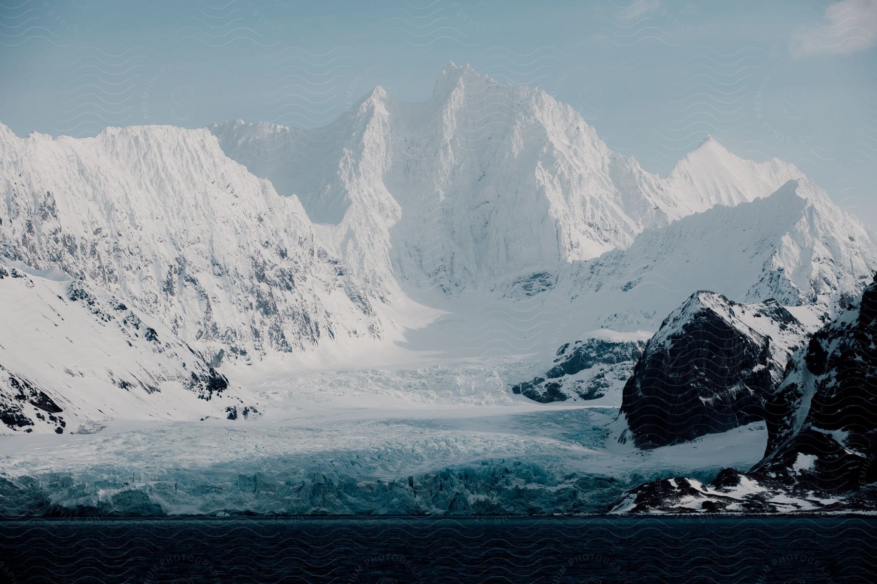 Snow covers a mountain range with a large bowllike valley on a partlycloudy day