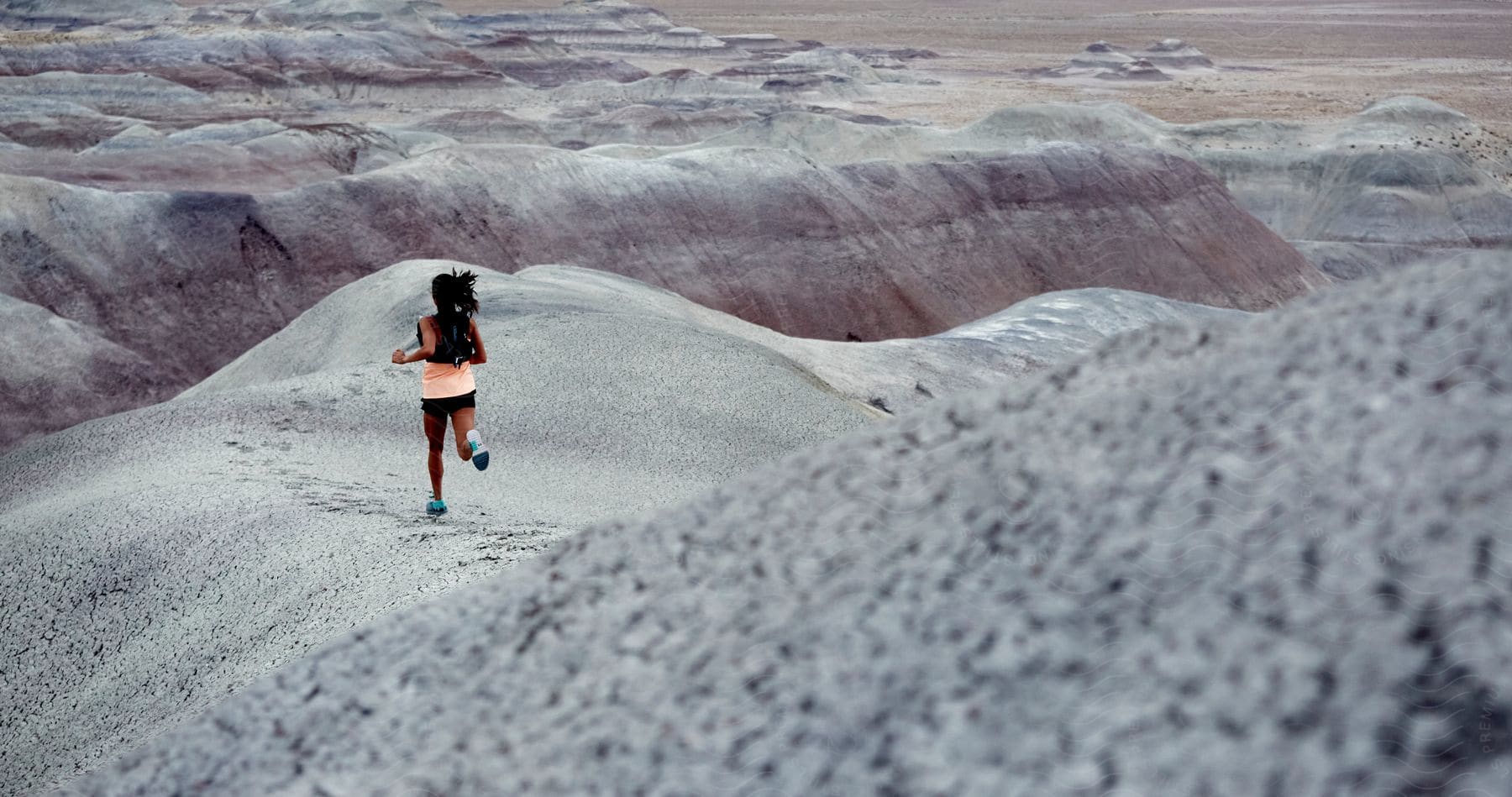 A black woman running through rocky desert hills