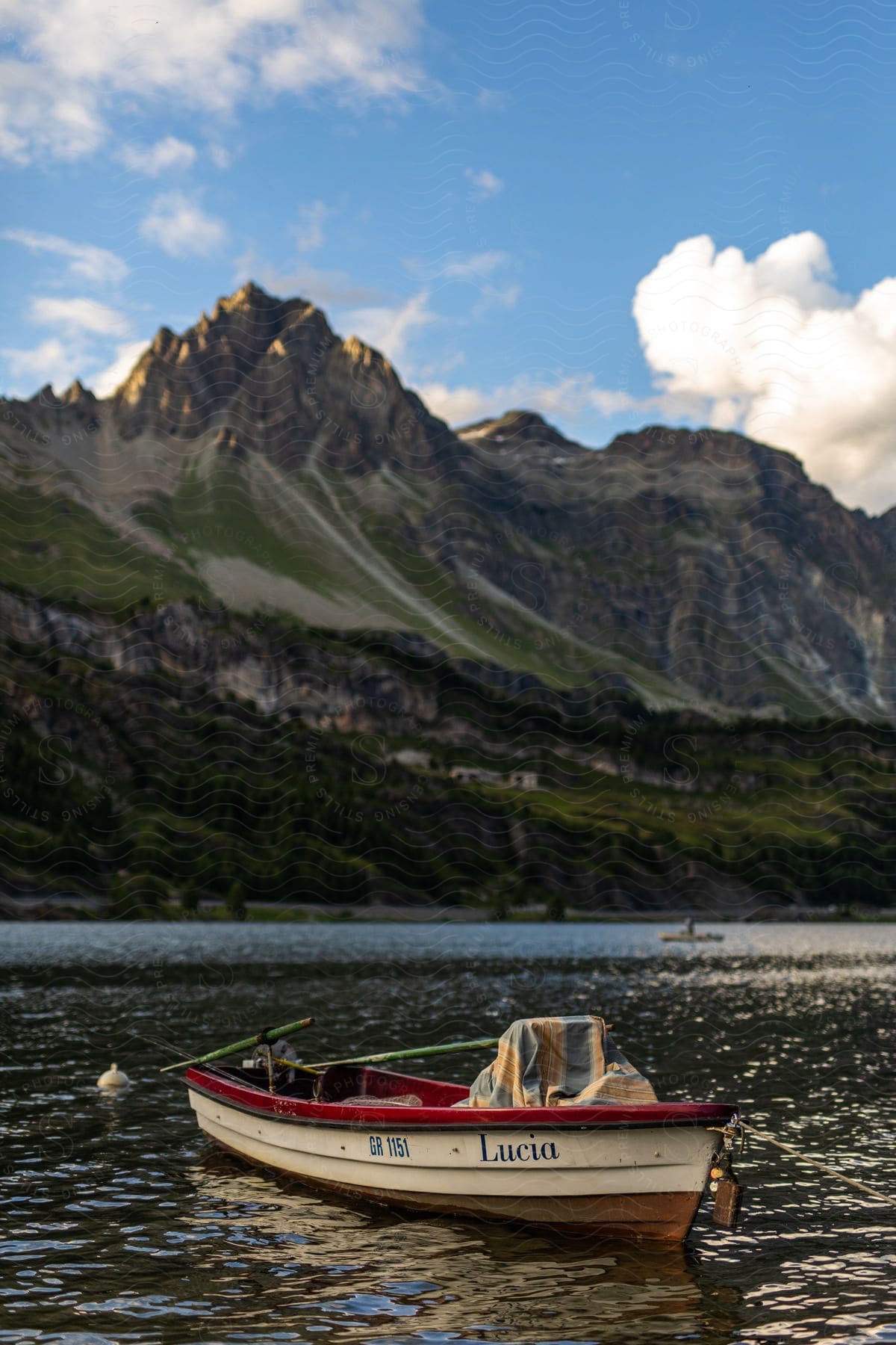 An empty row boat is stopped in a lake below a mountain