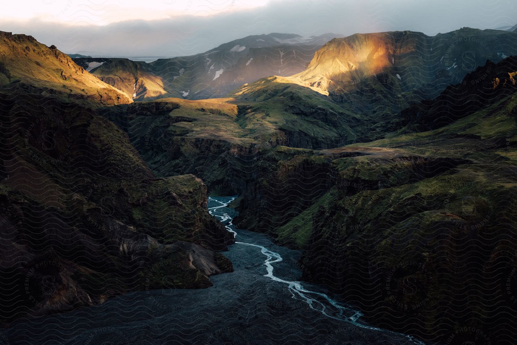 A river flows between mountains on a cloudy day