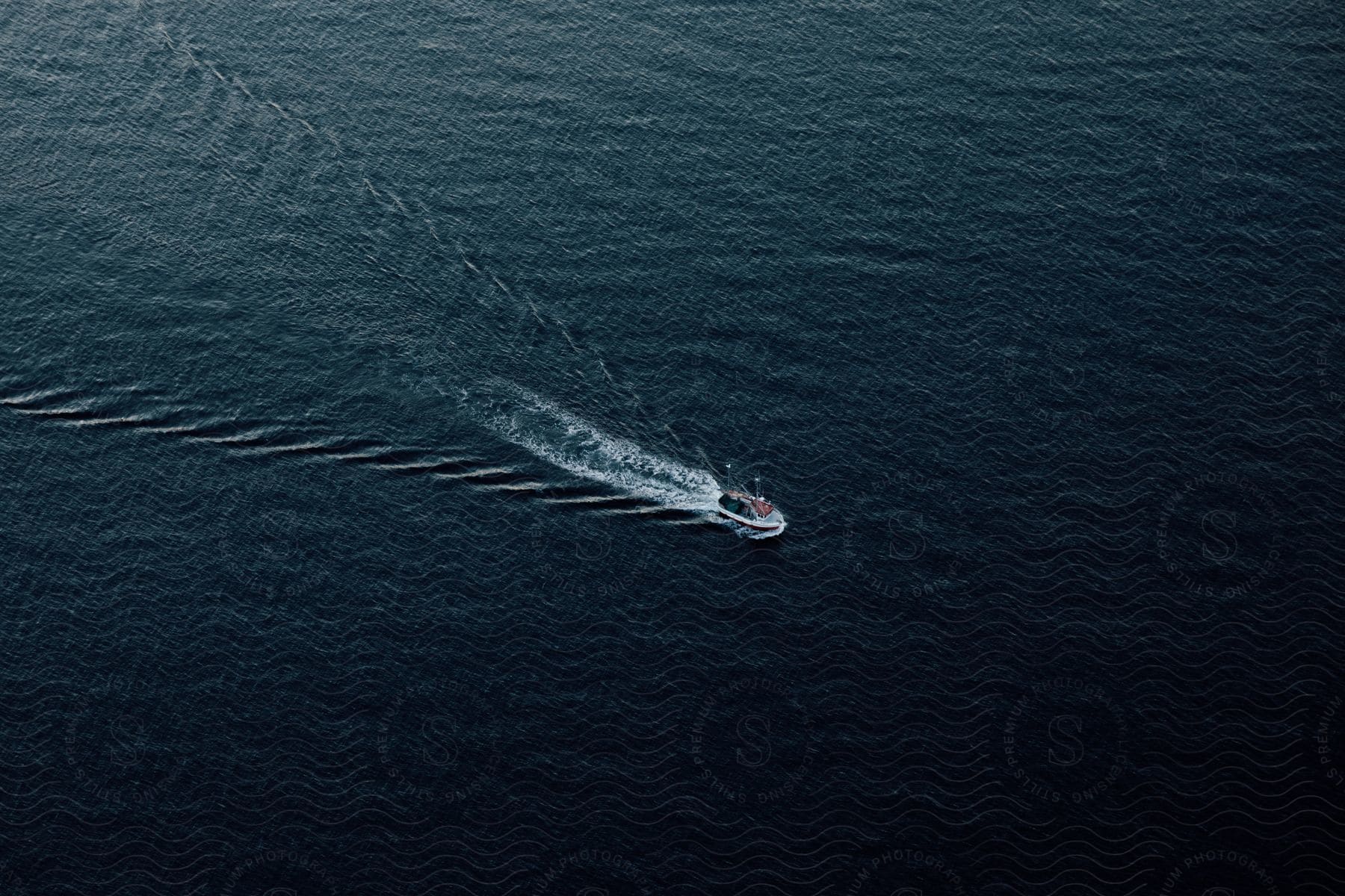 A boat moves on the surface of the ocean from an aerial perspective