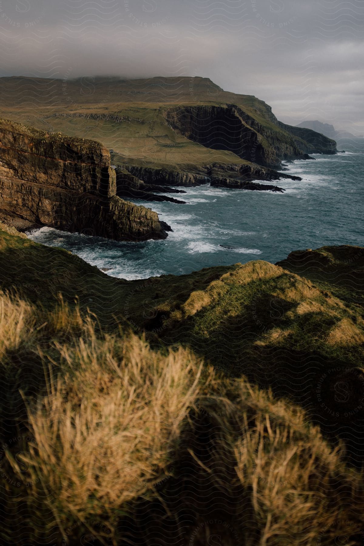 Mountain cliffs and rock formations stretch along the coast under a cloudy sky