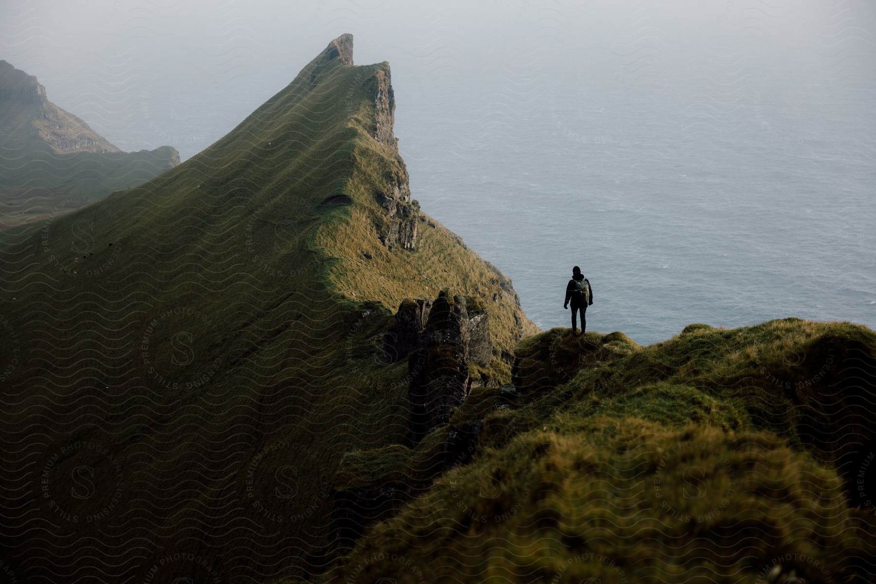 A man standing on top of a mountain overlooking the ocean