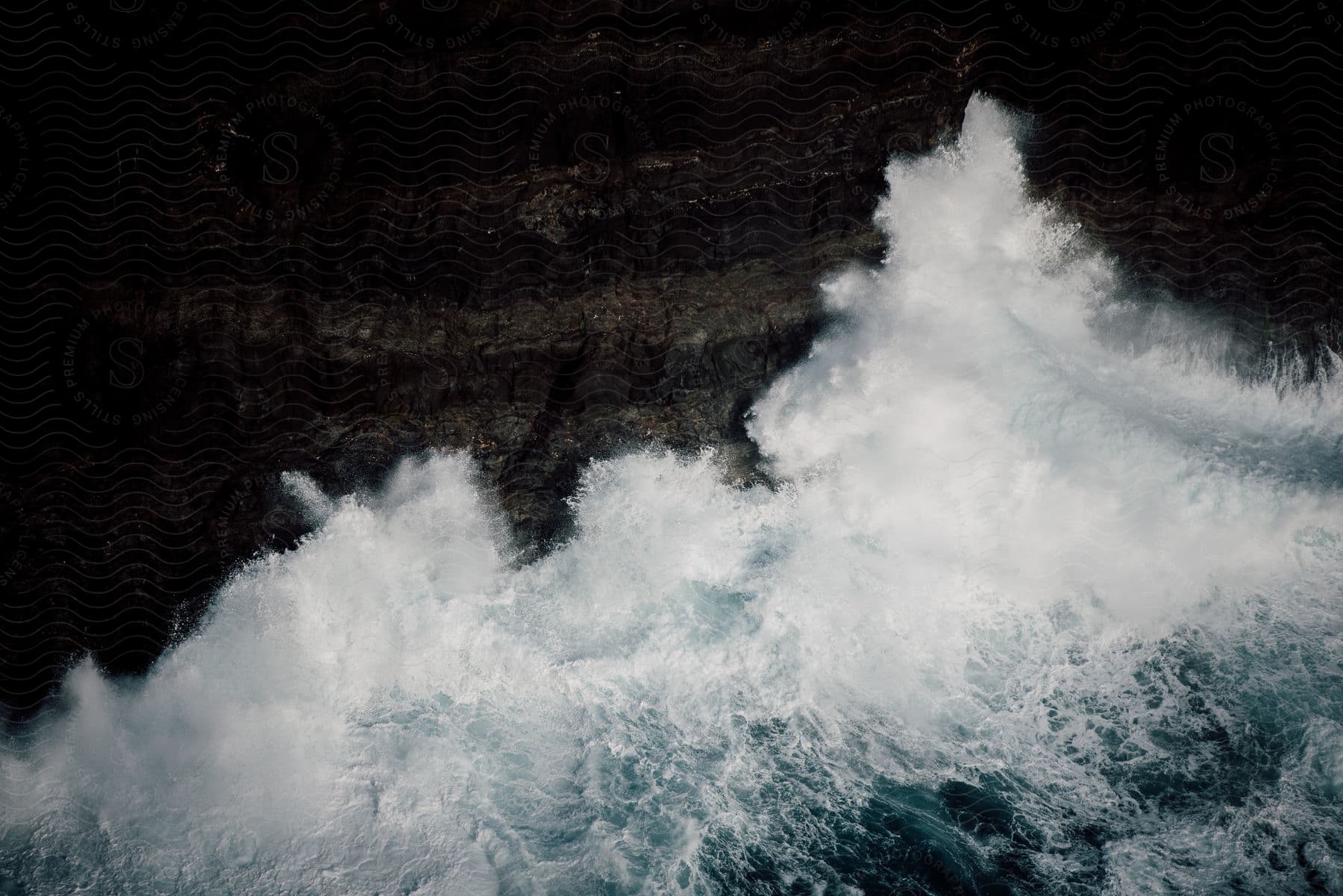 Water splashes as waves crash into rocks along the coast