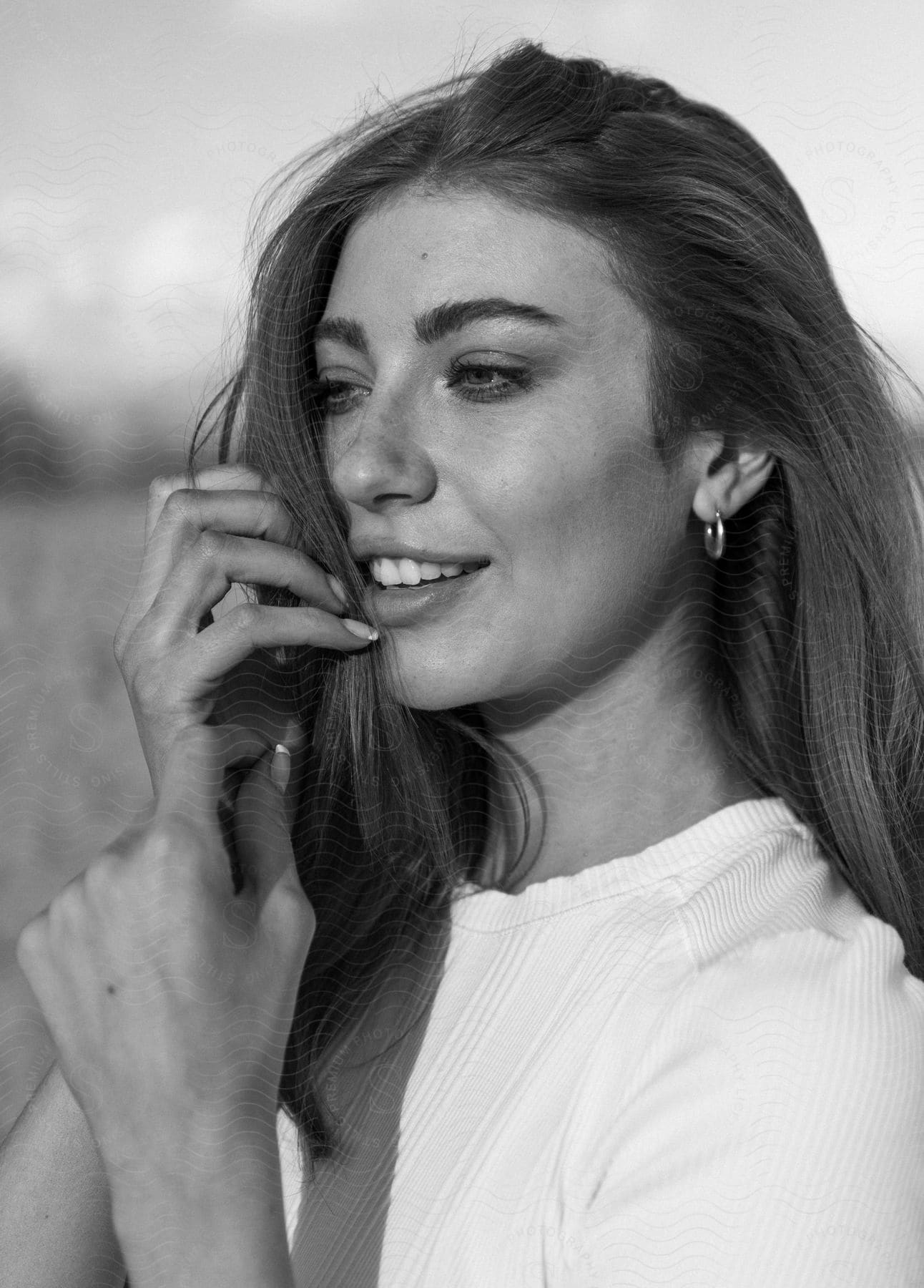 A black and white photograph of a smiling woman outdoors