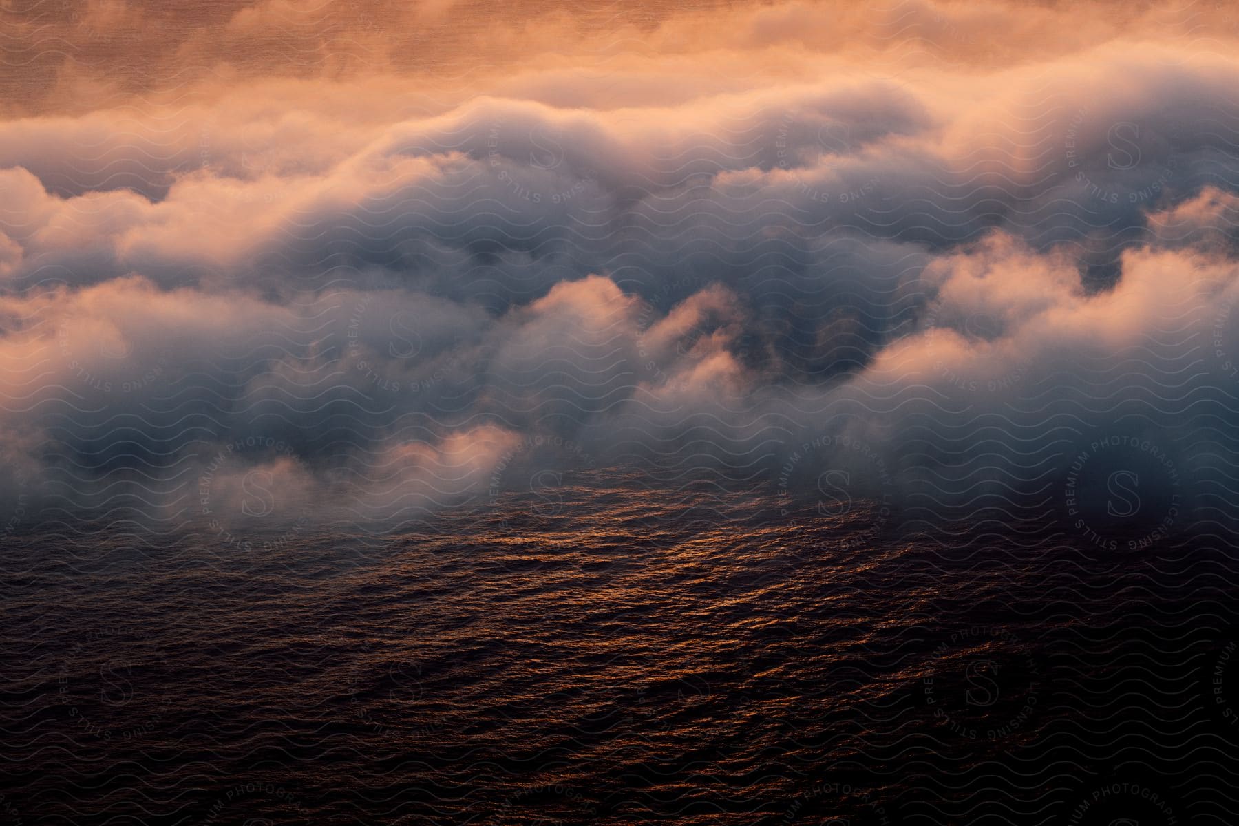 Low clouds rolling across the ocean at sunset