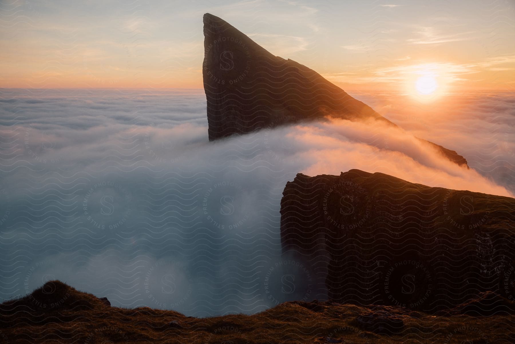 A mountain peak emerges from the clouds at dawn in a natural landscape