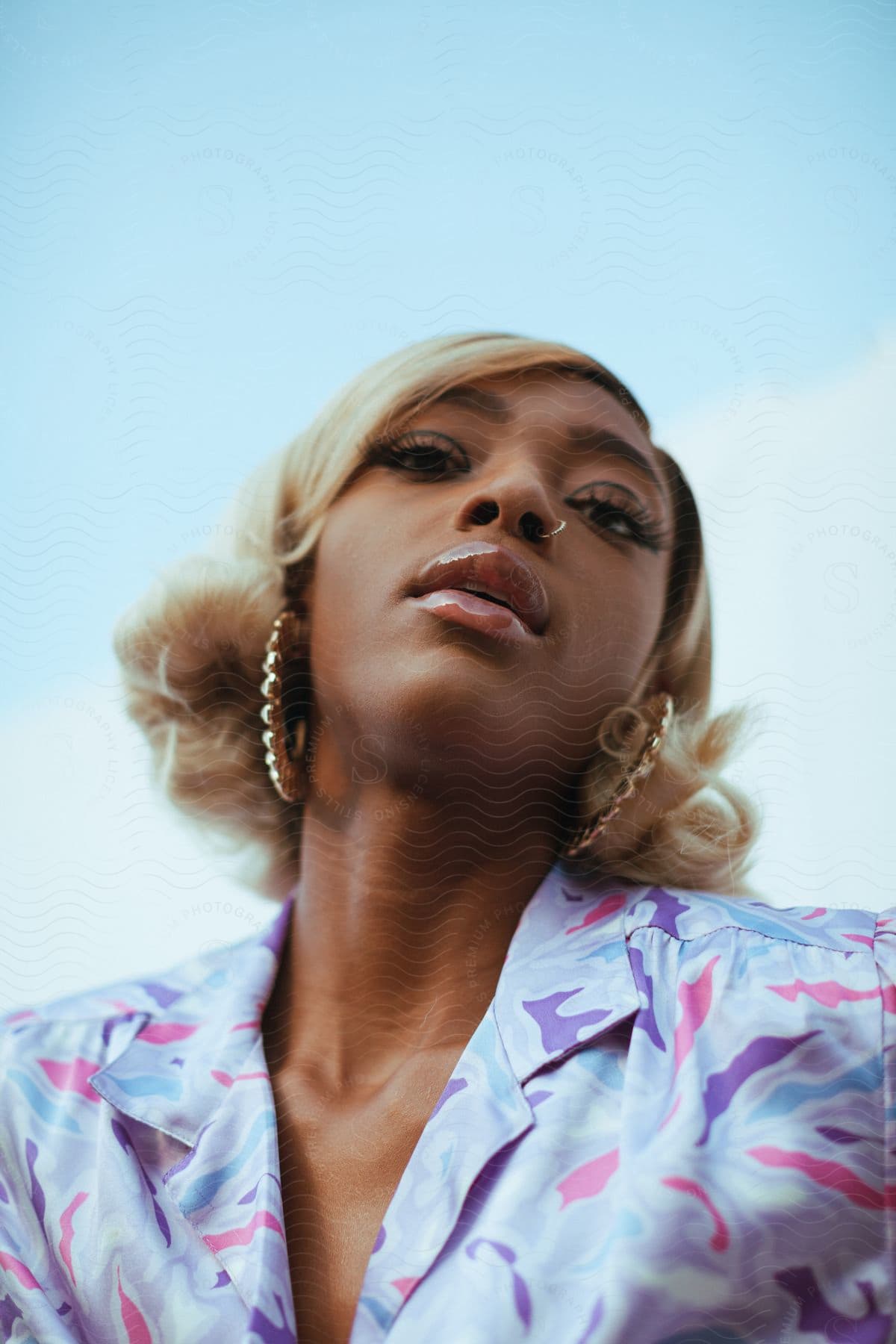 A confident black woman with blonde hair and earrings stares into the camera