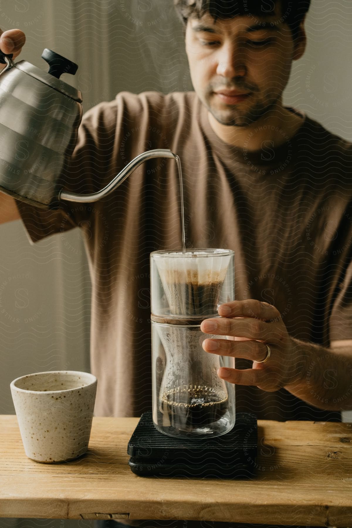 A man makes coffee using a drip system