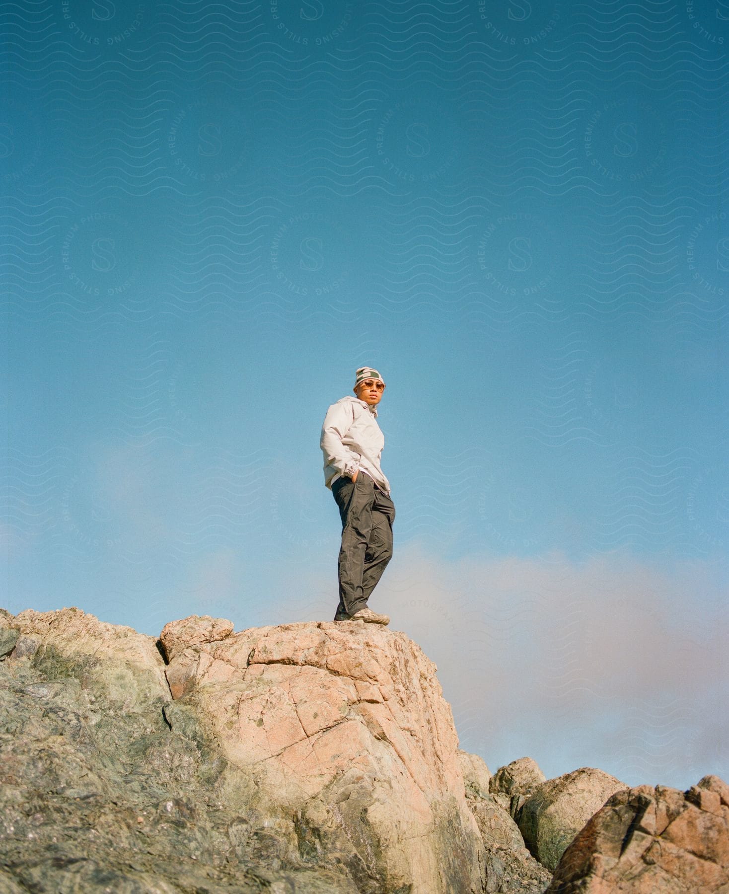 Man wearing sunglasses standing on top of a rock outdoors