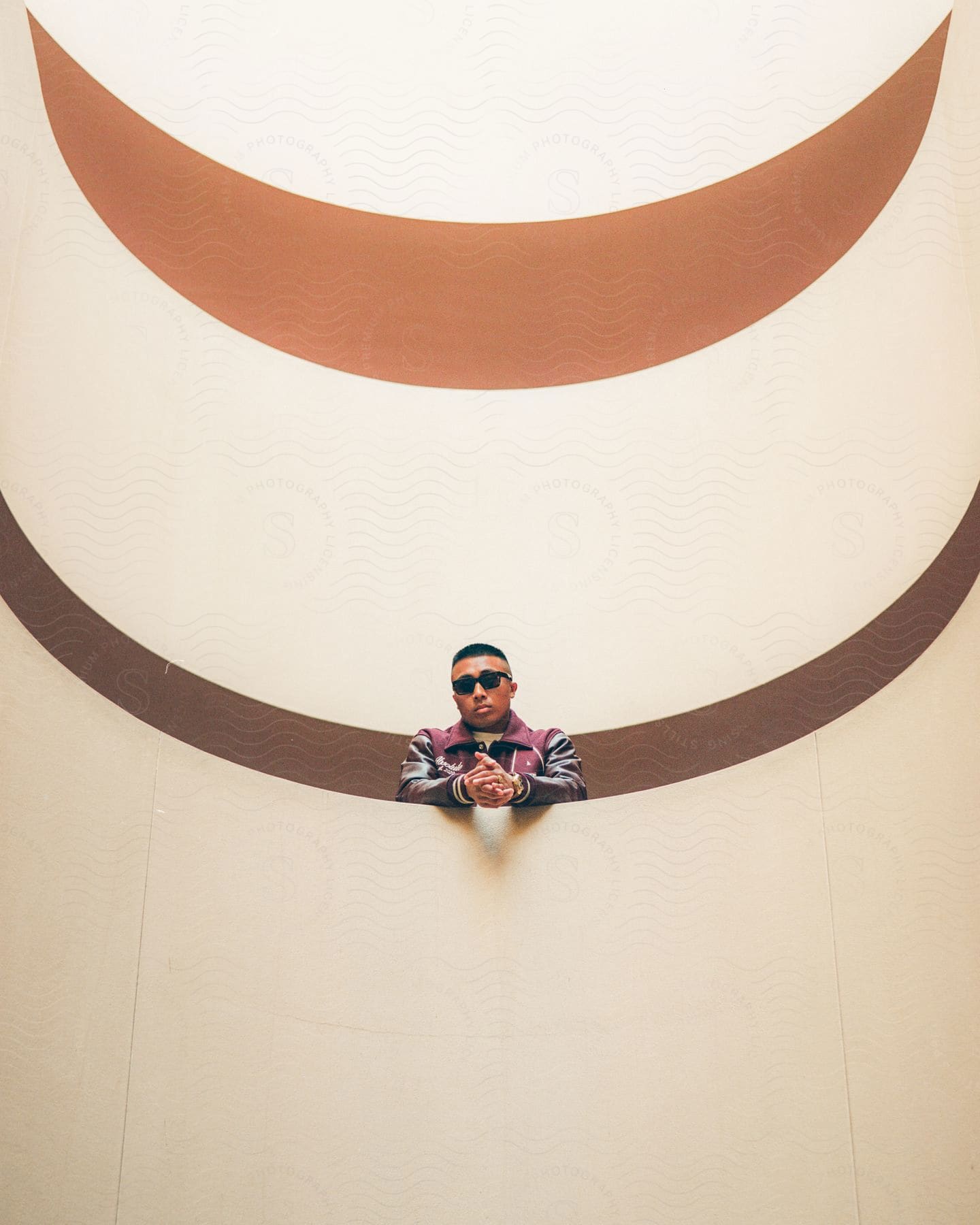 A man looking down from a balcony in a modernist building