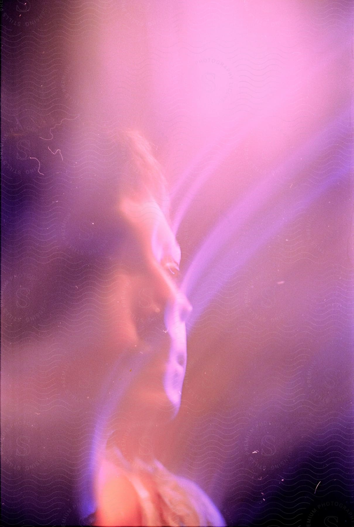 Close up of a young mans face creating color trails under violet lights